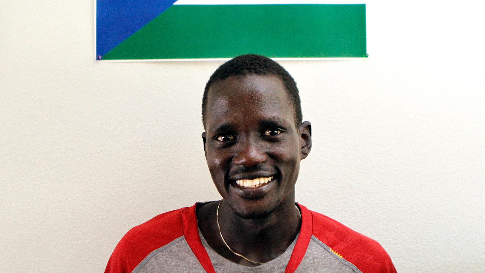 Guor Marial, 28, smiles in his apartment under a South Sudan flag in Flagstaff, Arizona July 21, 2012. The marathon runner born in what is now South Sudan ran under the Olympic flag in London.