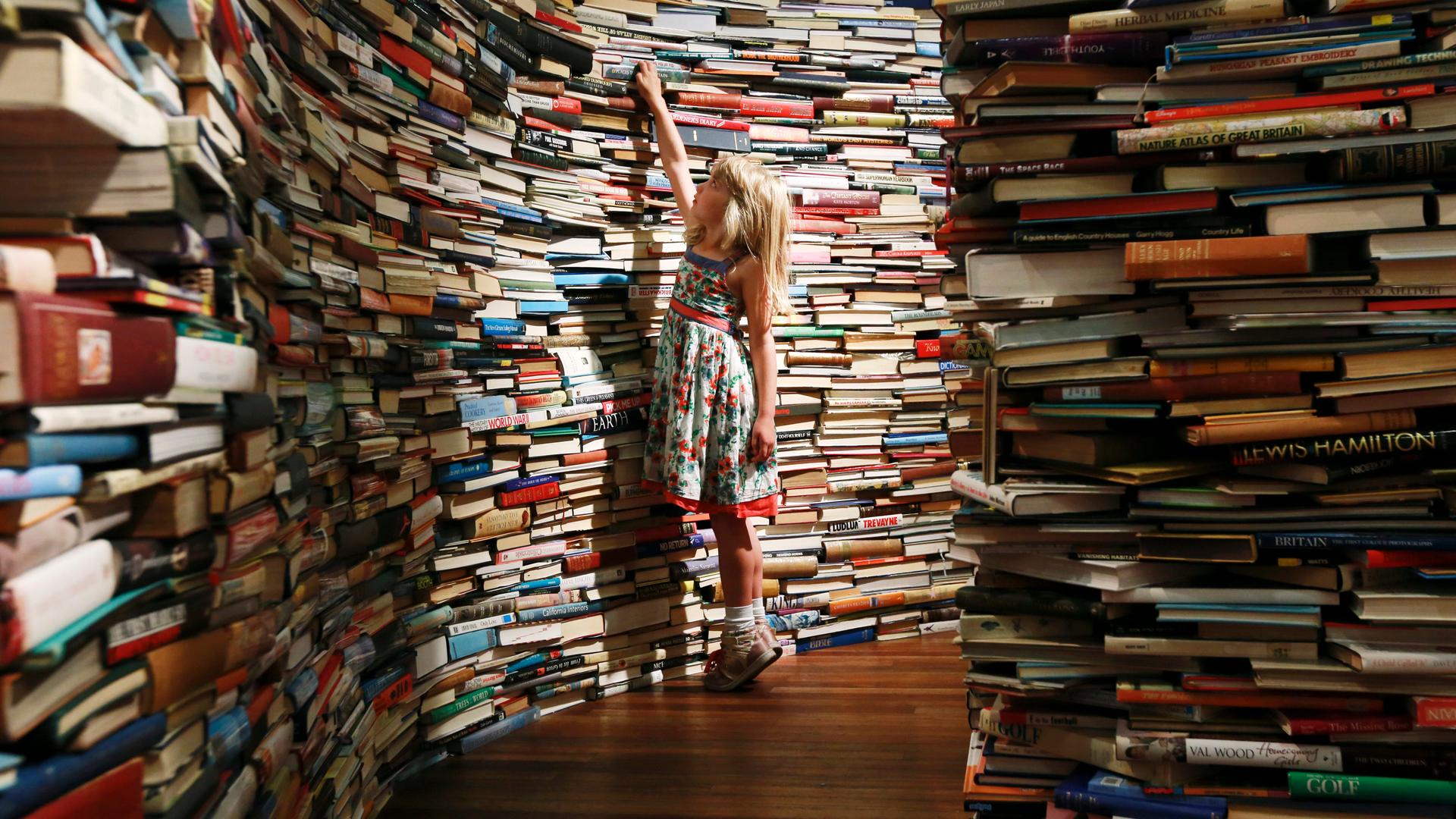 Leona, 7, poses inside a labyrinth installation made up of 250,000 books titled "aMAZEme" by Marcos Saboya and Gualter Pupo at the Royal Festival Hall in central London July 31, 2012.