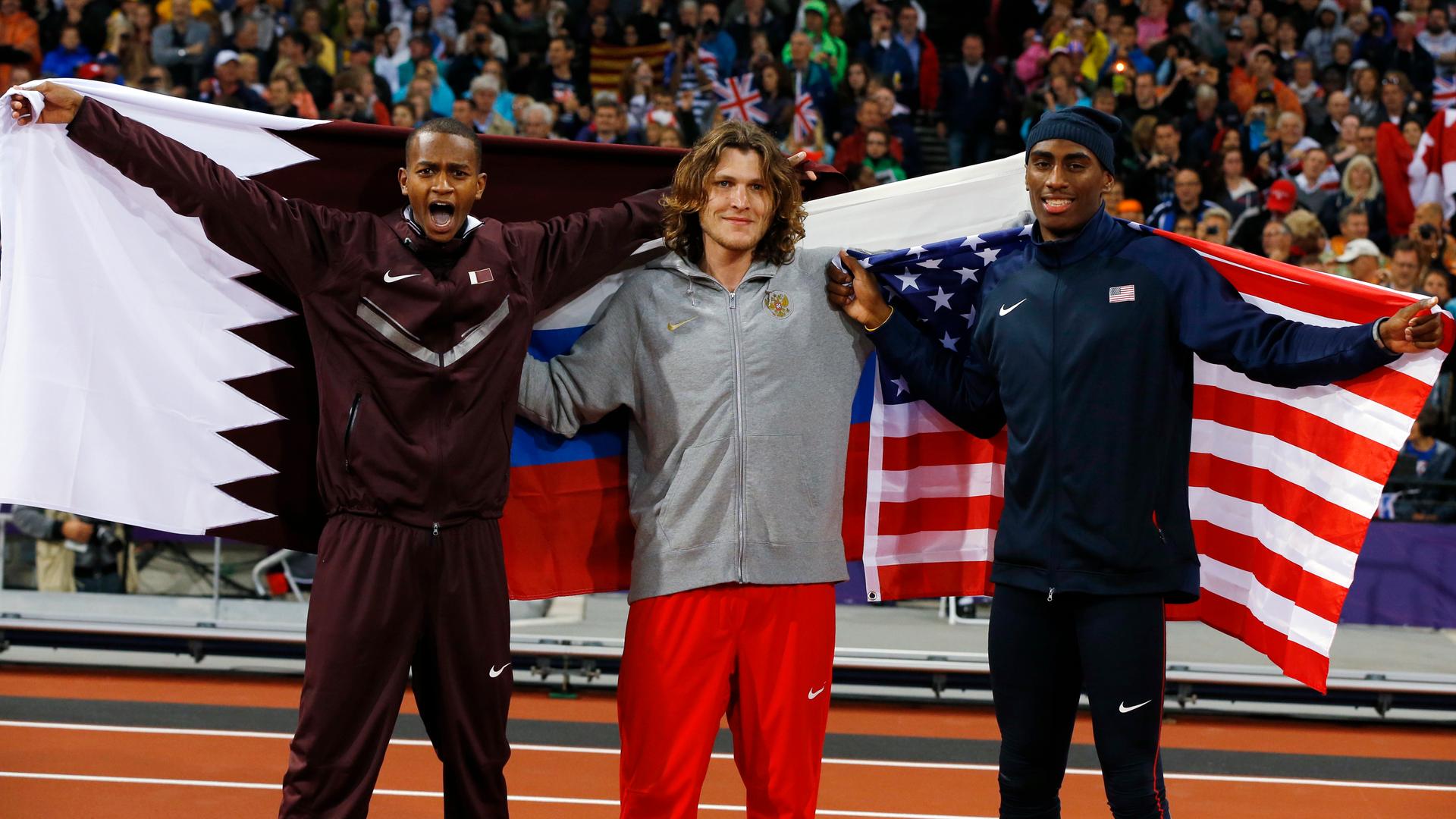 Gold medallist Russia's Ivan Ukhov, silver medallist Erik Kynard of the U.S. (R) and bronze medallist Qatar's Mutaz Essa Barshim (L) hold their national flags after the men's high jump final during the London 2012 Olympic Games.