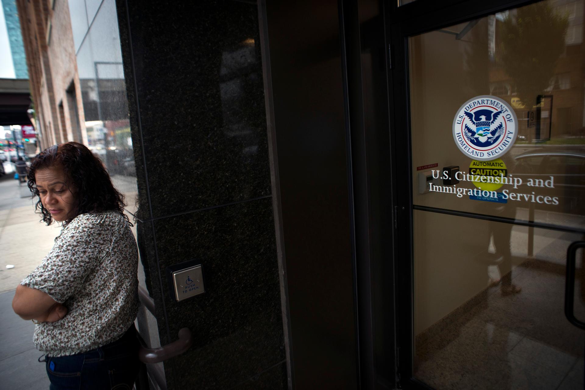 A woman stands in front of the doors of the US Citizenship and Immigration Services offices in New York.