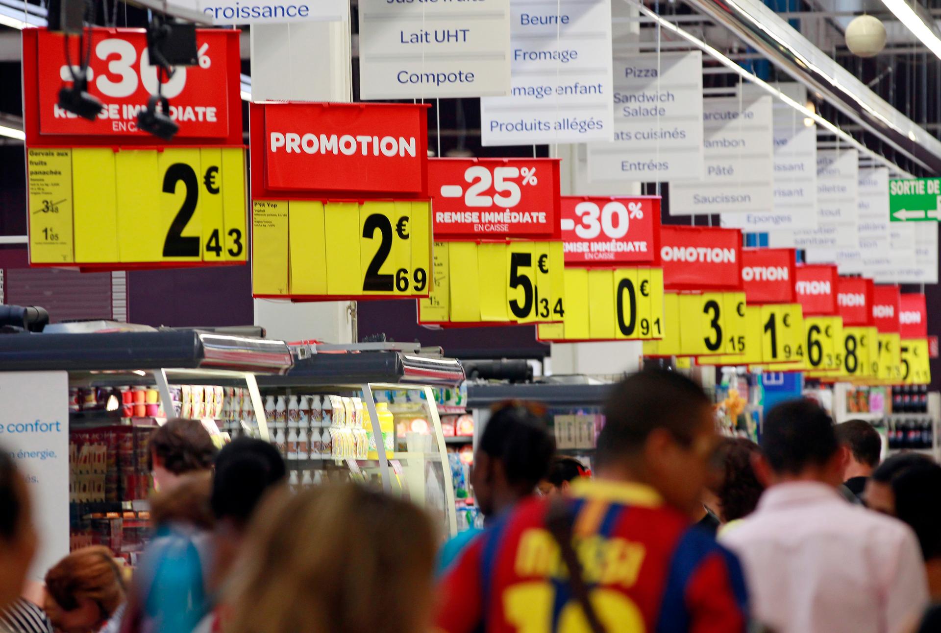 Customers walk past discount signs in a supermarket in Nice August 23, 2012