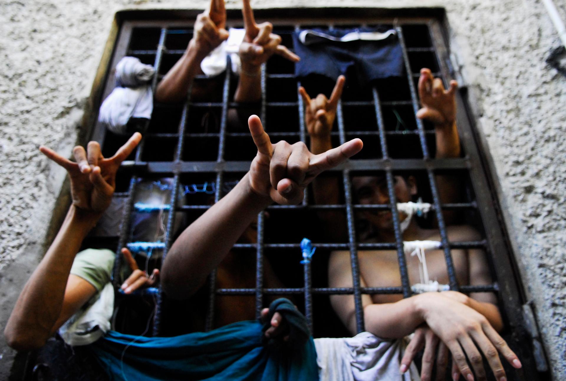 Prisoners flash the MS-13 Mara Salvatrucha street gang hand sign from inside a jail cell at a police station in San Salvador.