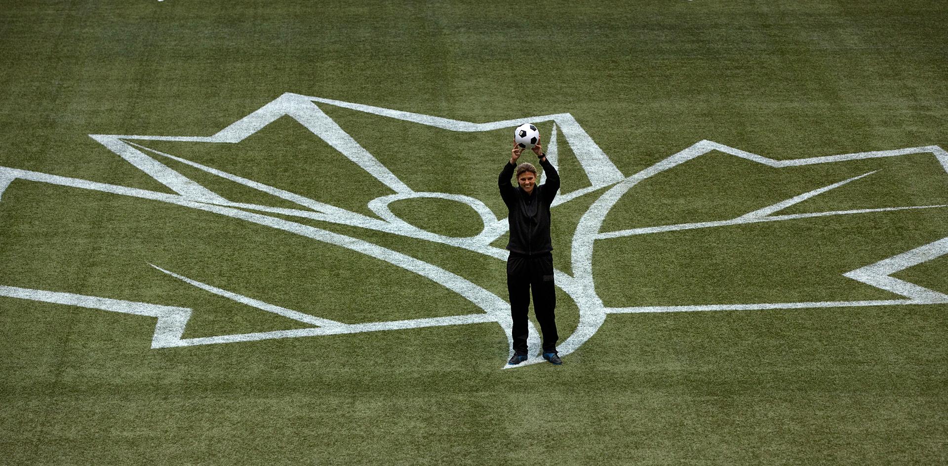 Canadian National Women's Soccer team captain Christine Sinclair poses with the logo for the 2015 FIFA Women's World Cup on the artificial turf field at BC Place in Vancouver, British Columbia.