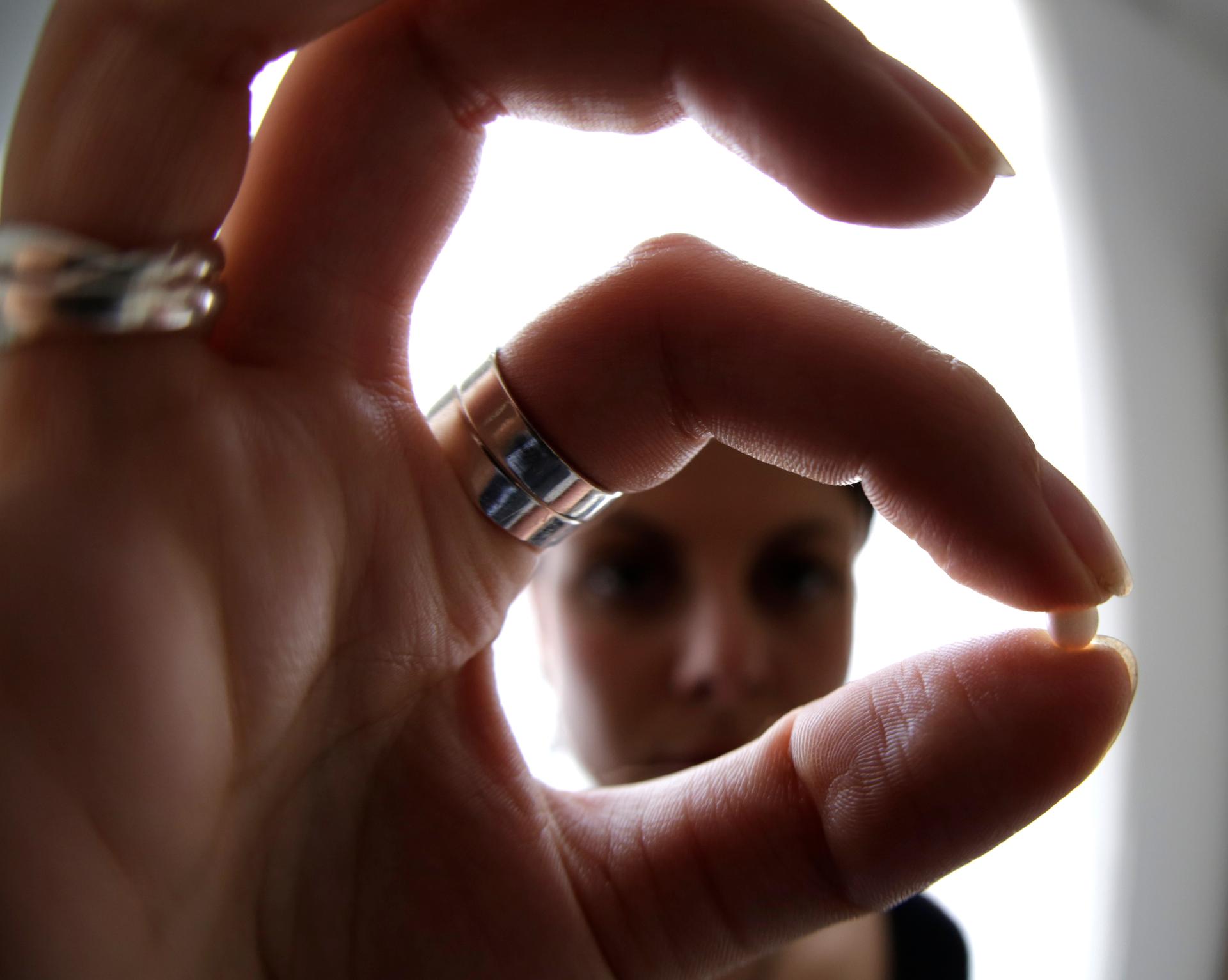 A woman holds a birth control pill at her home in Nice, France.