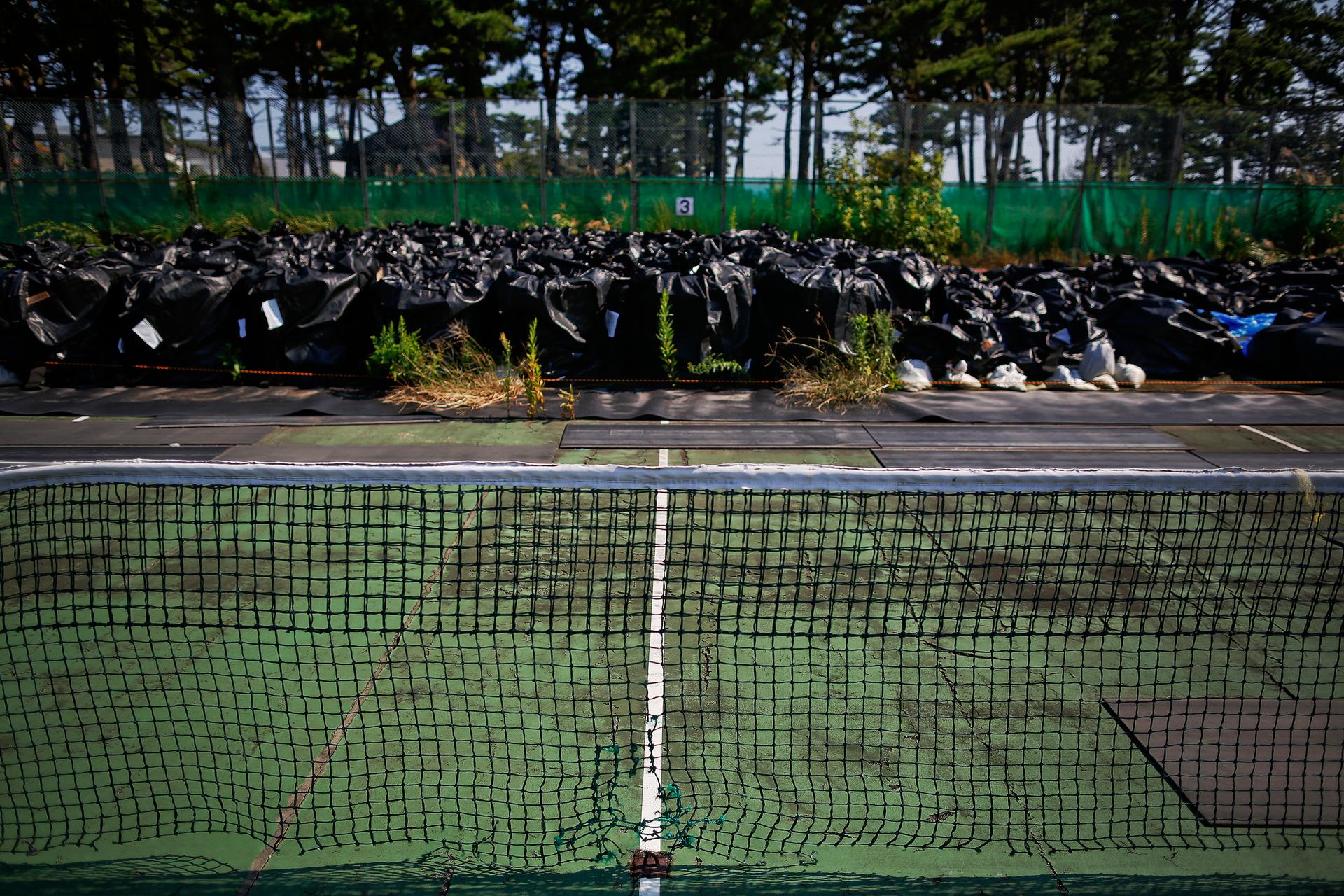 Big plastic bags containing radiated soil, leaves and debris are dumped at a tennis court at a sports park near the Fukushima Daiichi nuclear power plant