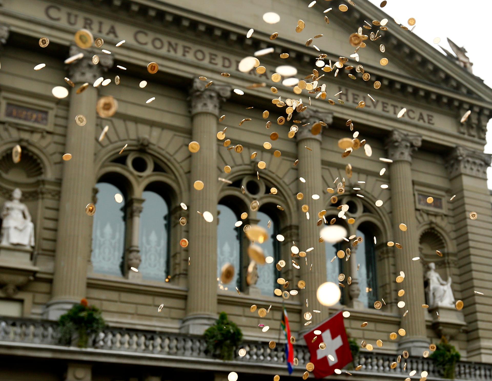 Five cent coins are pictured in the air in front of the Federal Palace in Bern, Switzerland, during an event organised by the committee that delivered 126,000 signatures to the parliament to propose a minimum monthly disposal household income of CHF 2,500