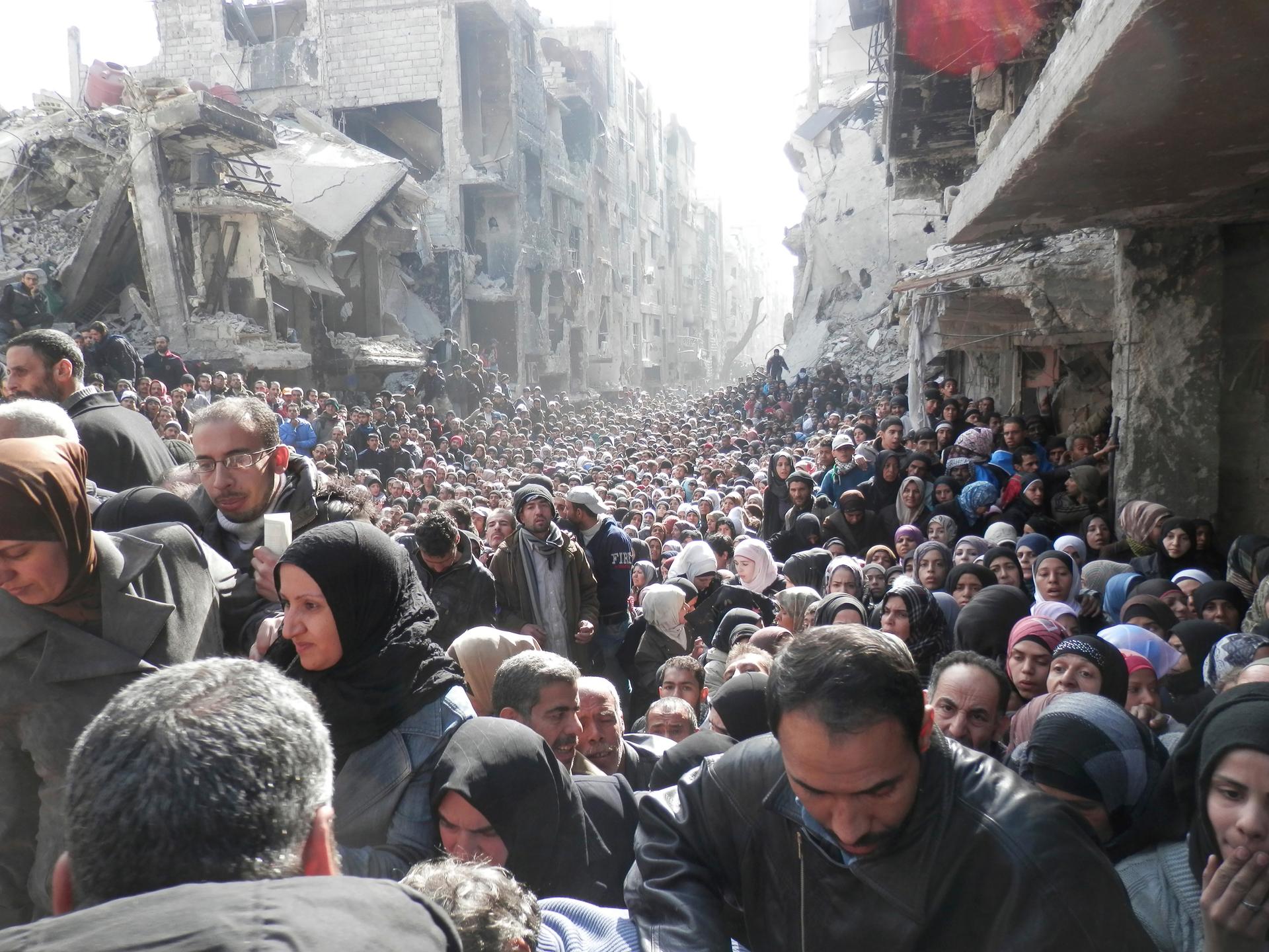 Residents wait to receive food aid distributed by the U.N. Relief and Works Agency (UNRWA) at the besieged al-Yarmouk camp, south of Damascus