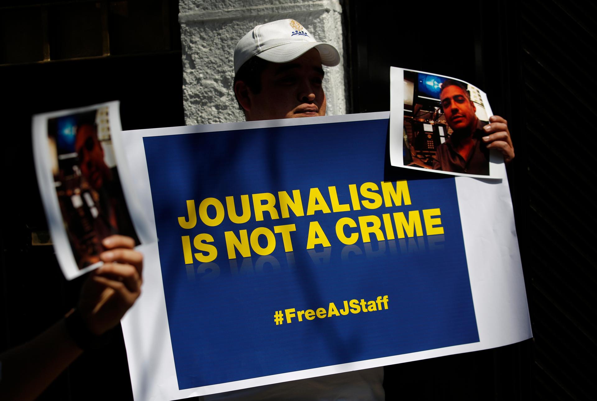 Protesters hold a sign and photographs of detained Al-Jazeera journalists Peter Greste, an Australian, Mohamed Fahmy, a Canadian-Egyptian national, and Baher Mohamed, an Egyptian. The three who were jailed in Cairo on December 29, 2013. Greste was release