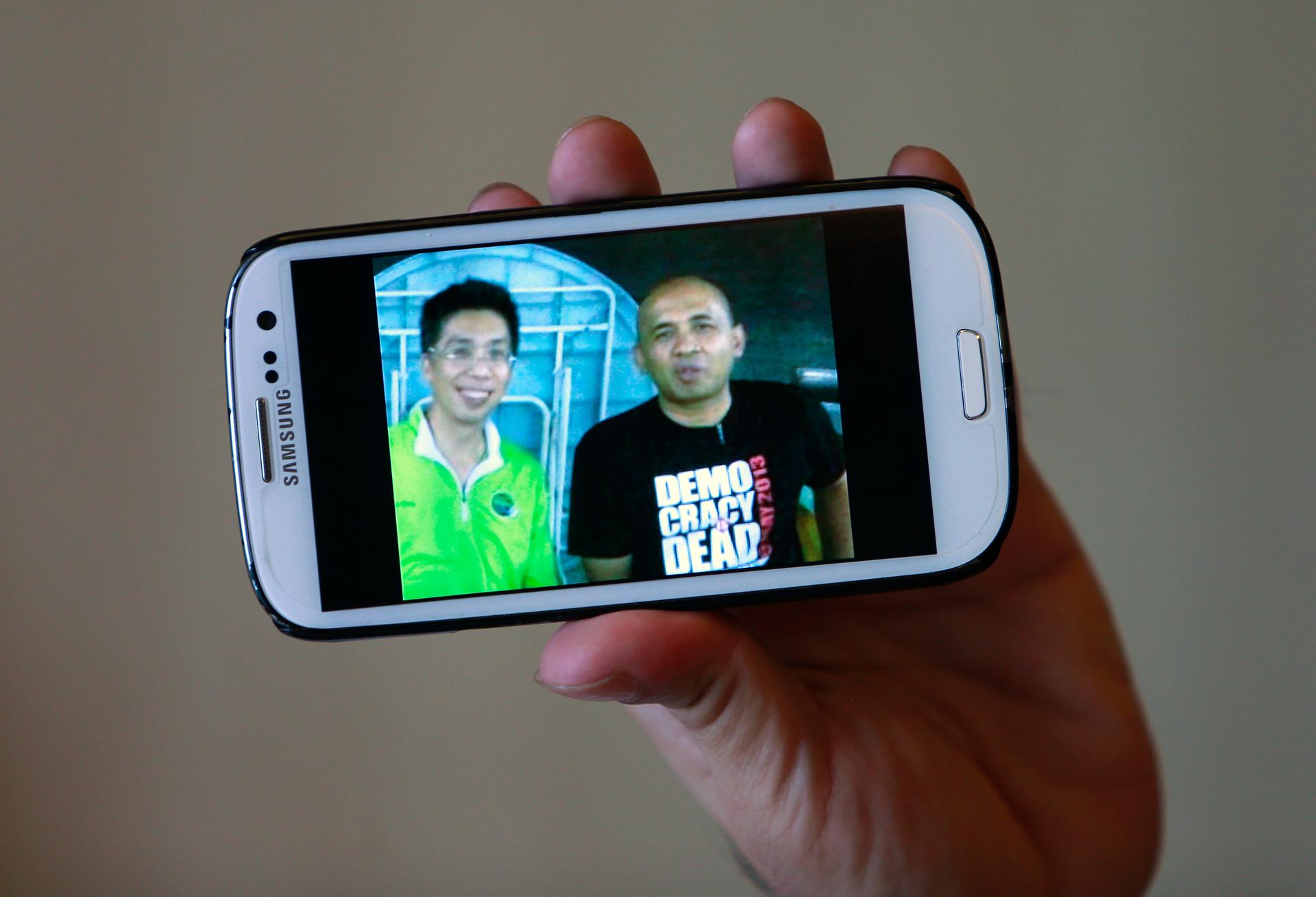 Peter Chong holds a smartphone displaying a picture of himself with missing Malaysia Airlines Flight MH370 captain Zaharie Shah.
