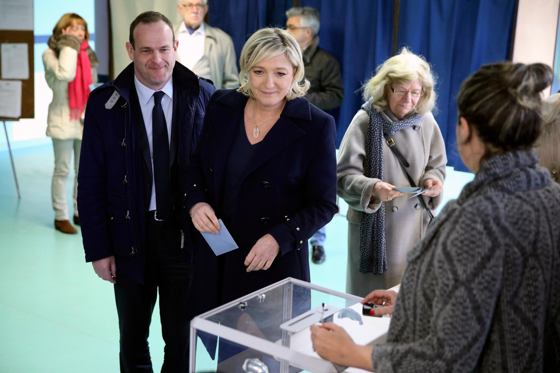 France's far-right National Front political party leader Marine Le Pen, center, prepares to cast her ballot at a polling station during the first round of the French mayoral elections in Henin Beaumont, Northern France, March 23, 2014. 