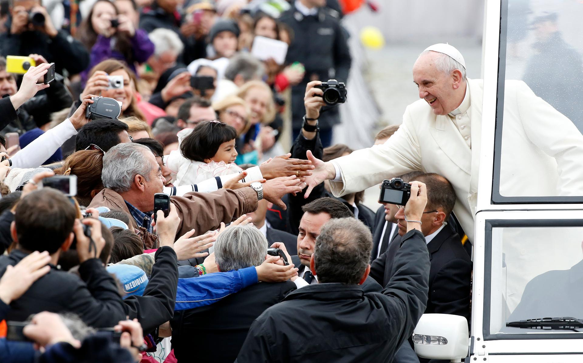 Pope Francis reaches out to greet the faithful in Saint Peter's Square at the Vatican on March 26, 2014.