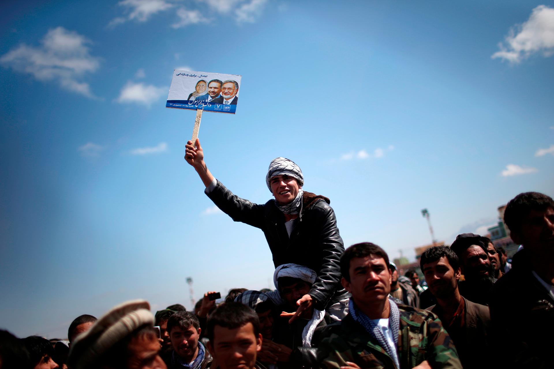 A supporter of Afghan presidential candidate Zalmai Rassoul holds his picture during an election rally in the city of Mazar-i-Shariff, in northern Afghanistan on March 27, 2014. The Afghan presidential election will be held on April 5.