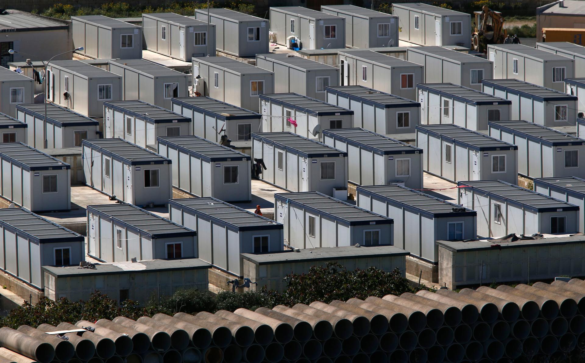 African immigrants walk among rows of prefabricated container houses, which have replaced scores of tents, at the open centre for immigrants formerly known as "Tent City" in Hal Far, outside Valletta March 27, 2014. In 2013