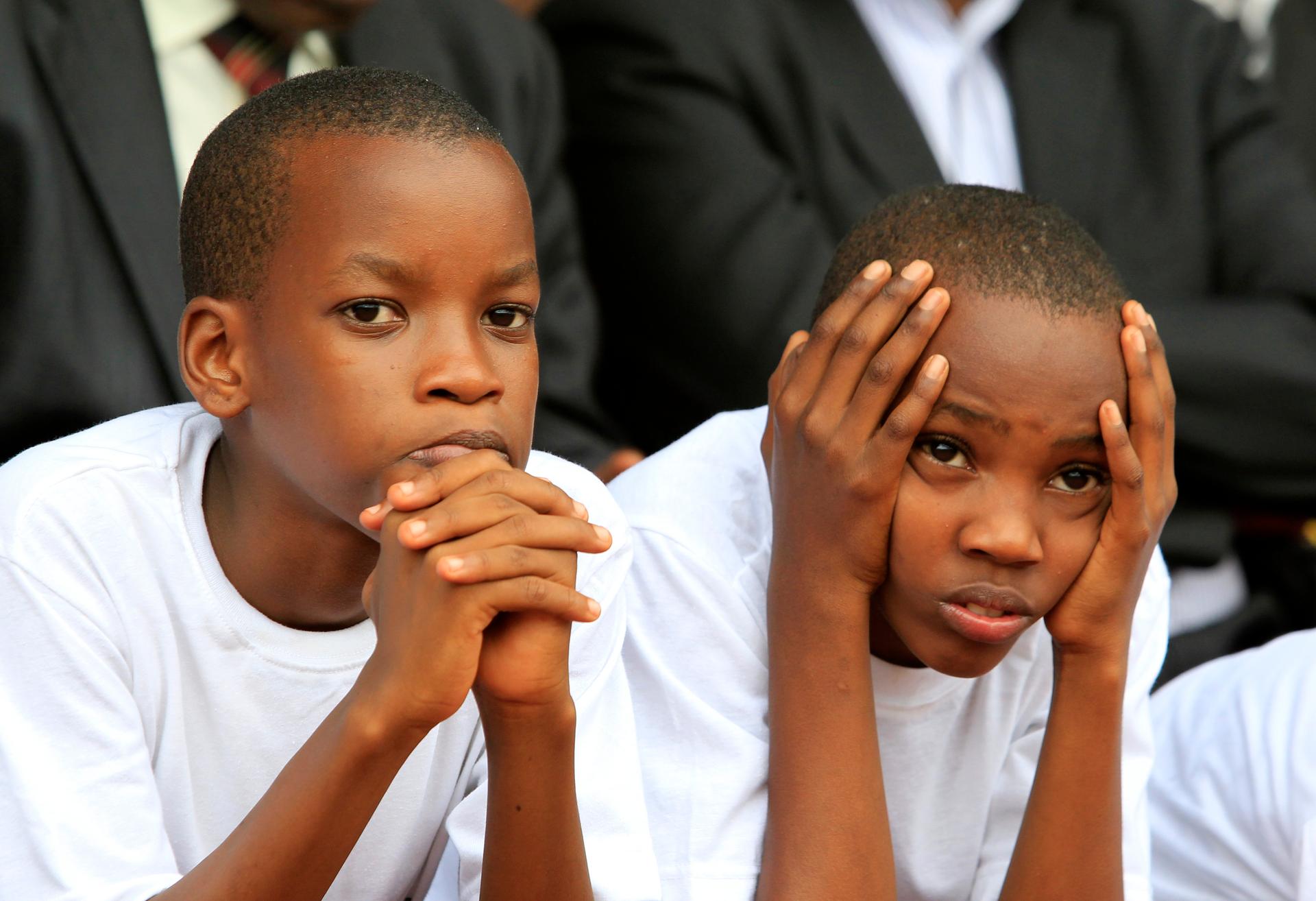 Rwandan boys watch as a flame is escorted through a Kigali suburb marking the 20th anniversary of the genocide.