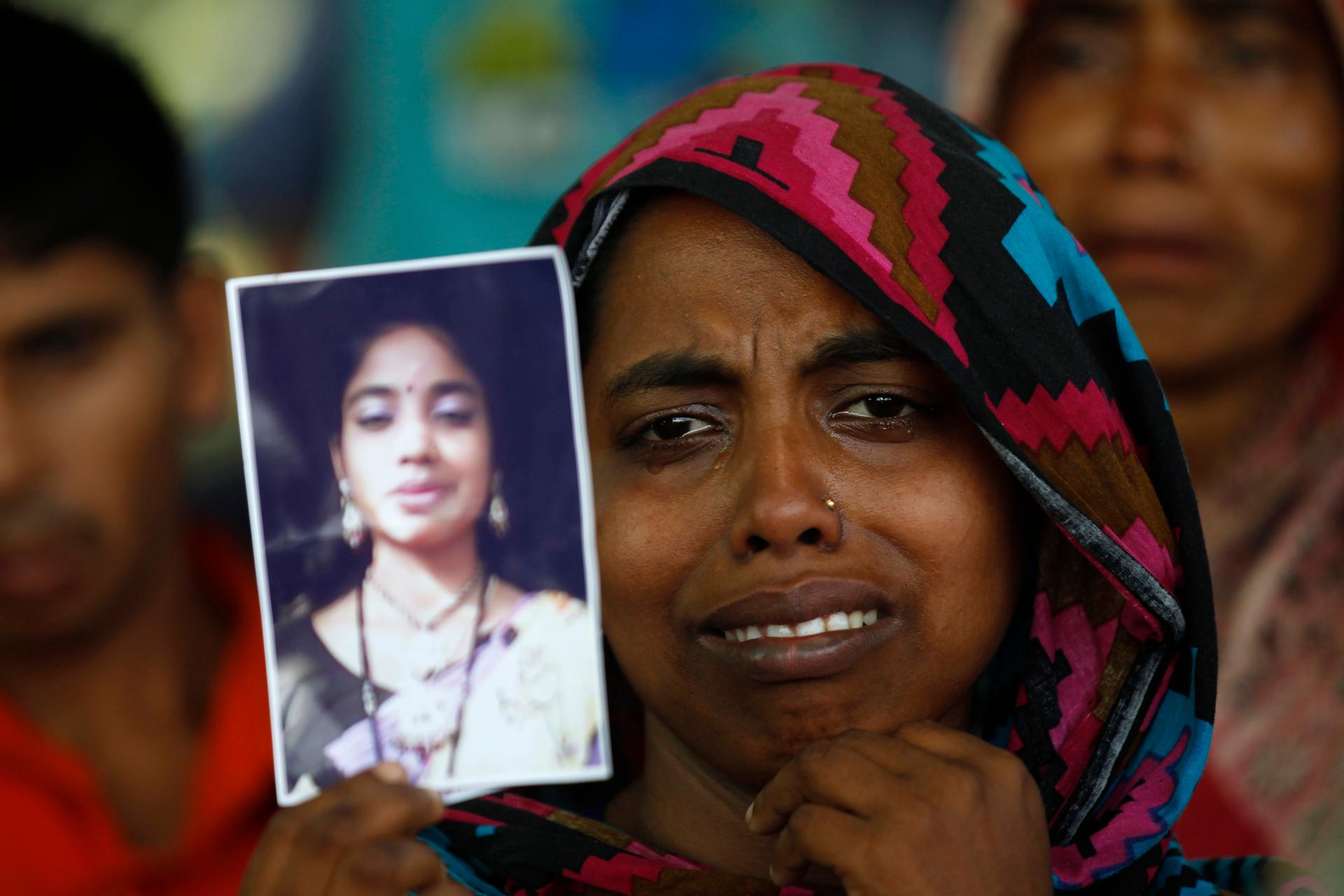 A woman holds a picture of her relative, a garment worker who went missing in the Rana Plaza collapse,  on the first year anniversary of the accident.