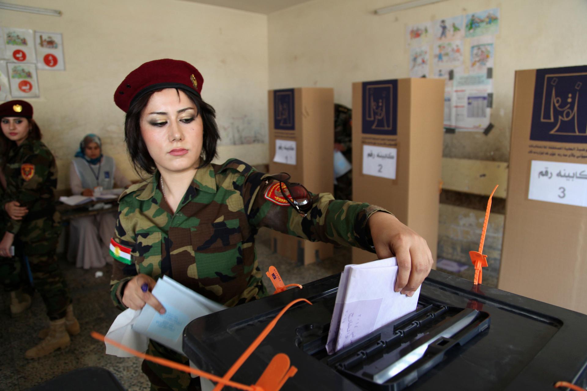 A member of Kurdish security forces casts her ballot inside a polling station during early voting for the parliamentary election in Irbil, in Iraq's Kurdistan region, on April 28, 2014.  