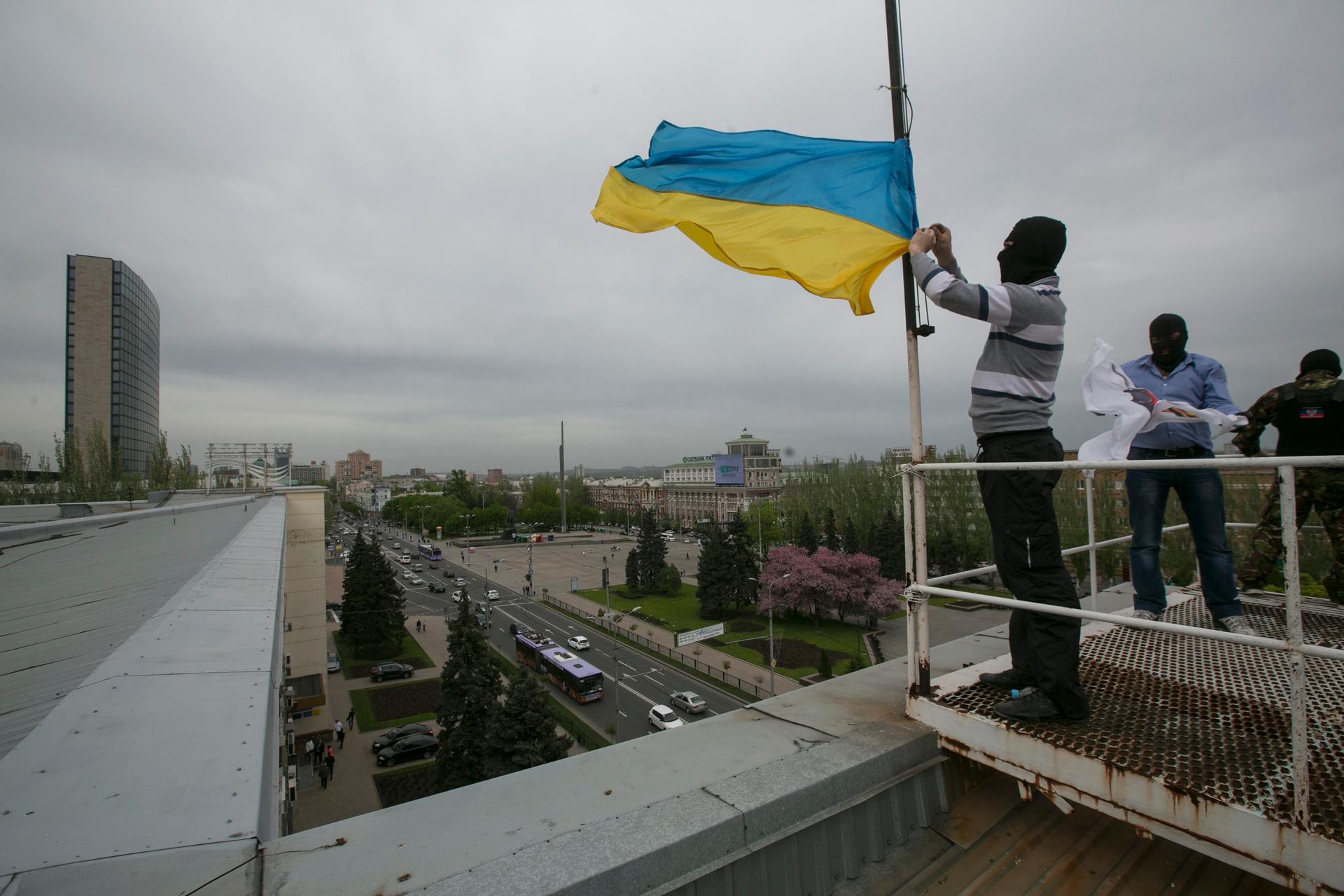 Masked pro-Russian activists haul down the Ukrainian flag from the top of another government building in eastern Ukraine, Monday.