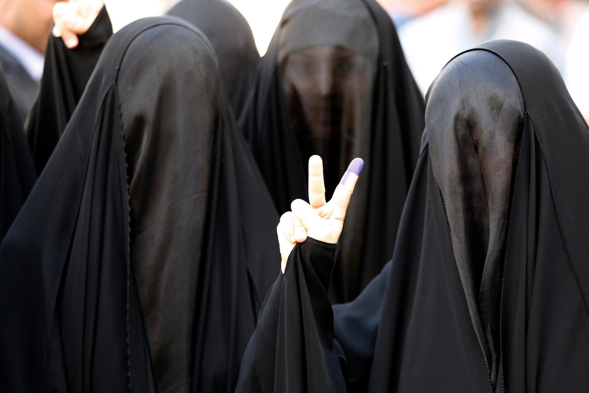 A woman in Baghdad shows her ink-stained finger after voting.