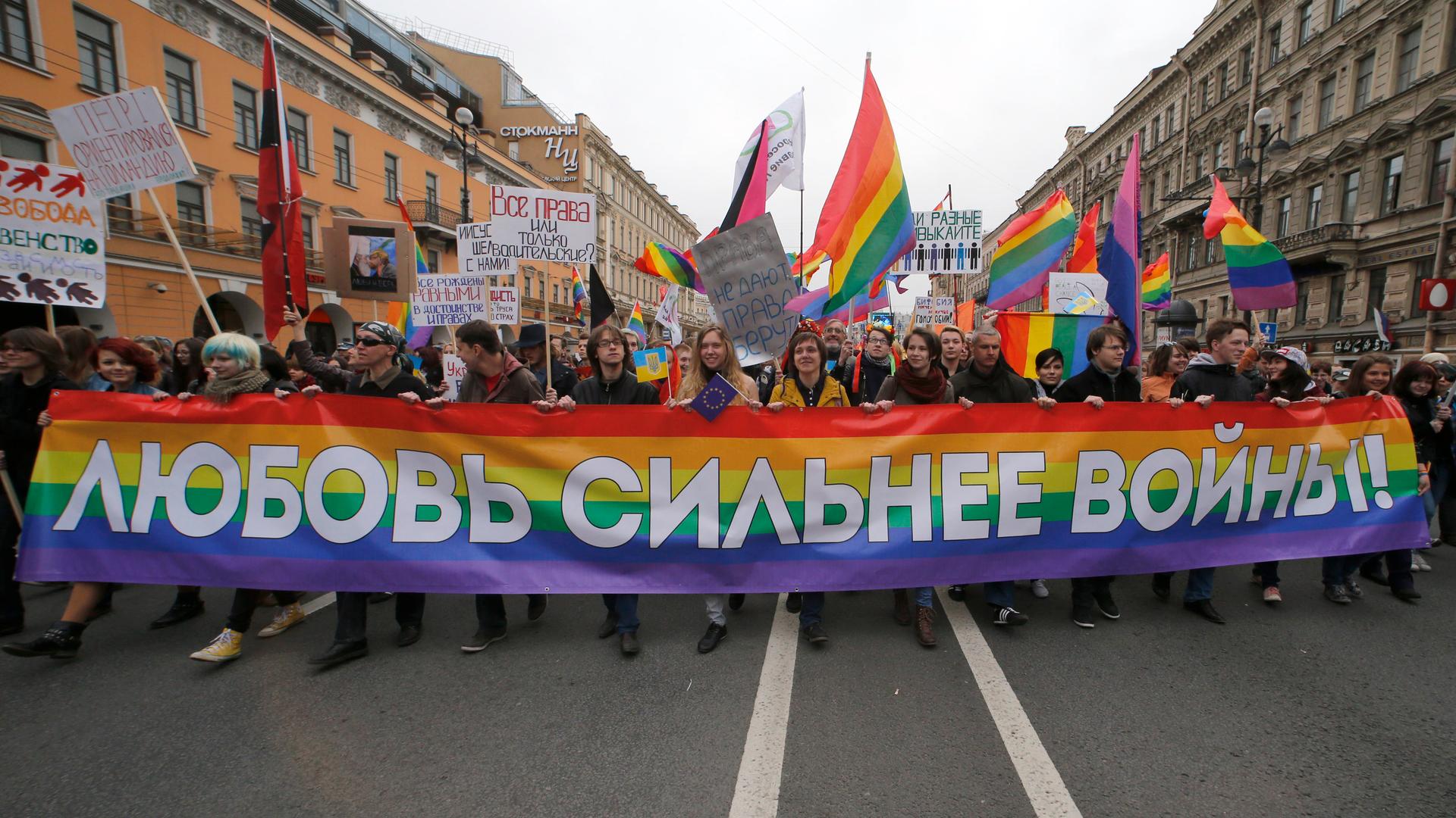 Gay rights activists march with a banner during a May Day rally in St. Petersburg. The banner reads, "Love is stronger than war!"