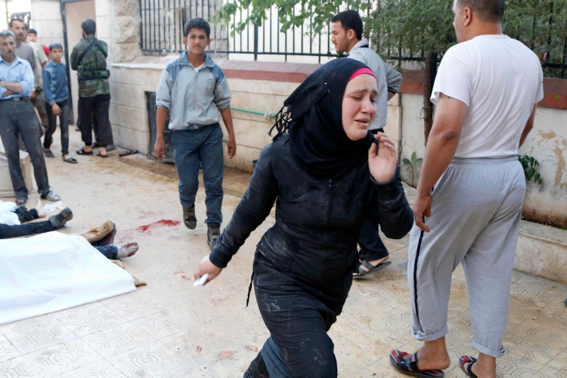 A woman runs past bodies after, according to activists, two barrel bombs were dropped by forces loyal to Syria's President Bashar Al-Assad in Aleppo, Friday.