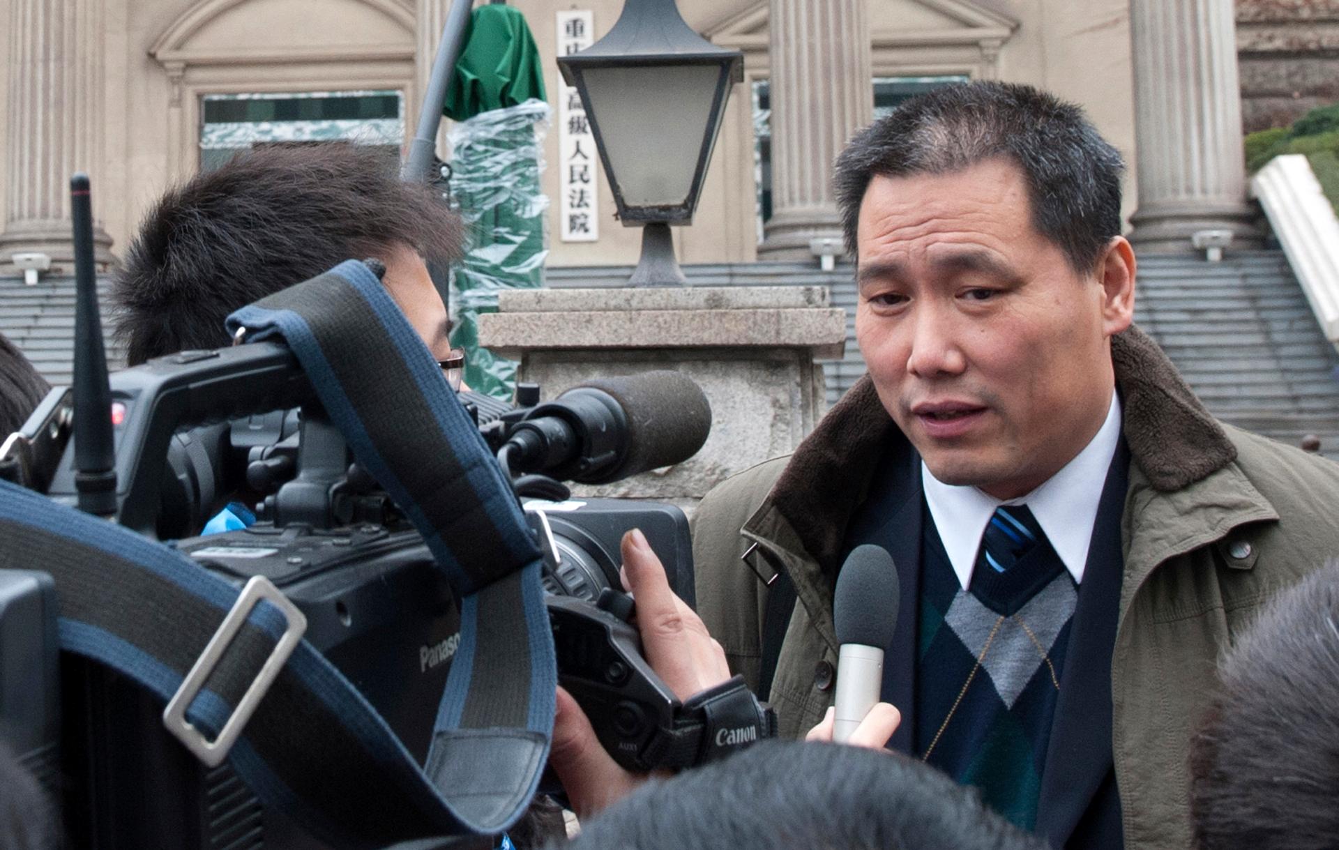 Chinese lawyer Pu Zhiqiang (right) speaks to journalists outside a Chinese courthouse on December 28, 2012. China has detained Pu, a prominent human rights lawyer, after he attended a meeting that urged a probe into the bloody suppression of pro-democracy