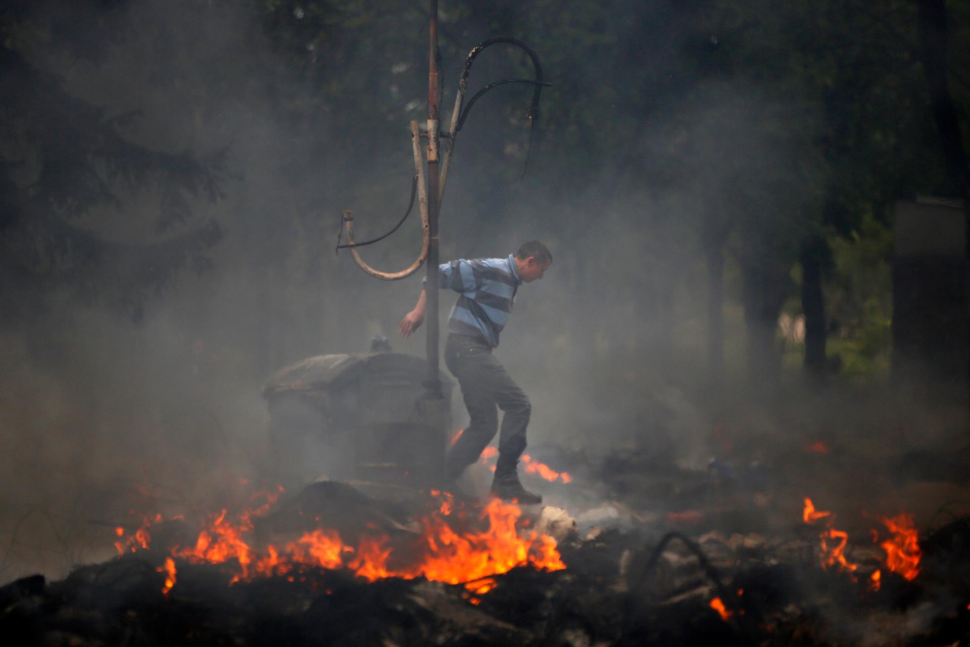 A man jumps over a burning barricade outside the city hall in Mariupol, Friday.