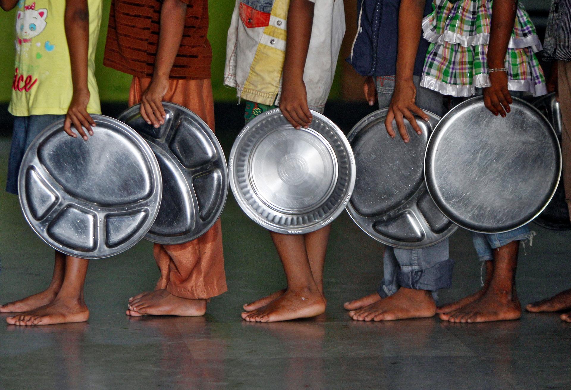 Children holding plates wait in a queue to receive food at an orphanage run by a non-governmental organisation in the southern Indian city of Chennai. 