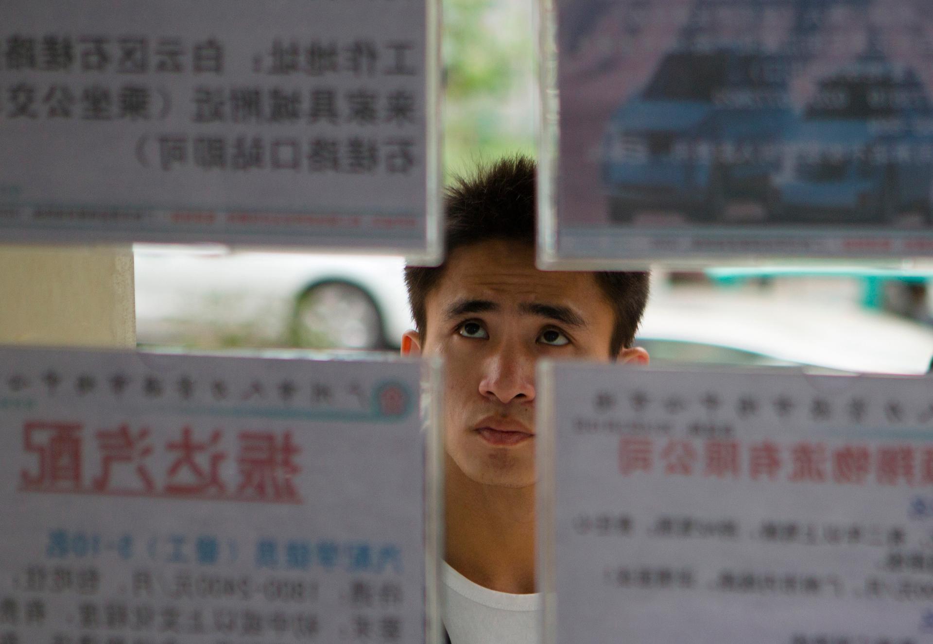 A job seeker looks at recruitment advertisements at a labor market in Guangdong province, where most people speak Cantonese. 