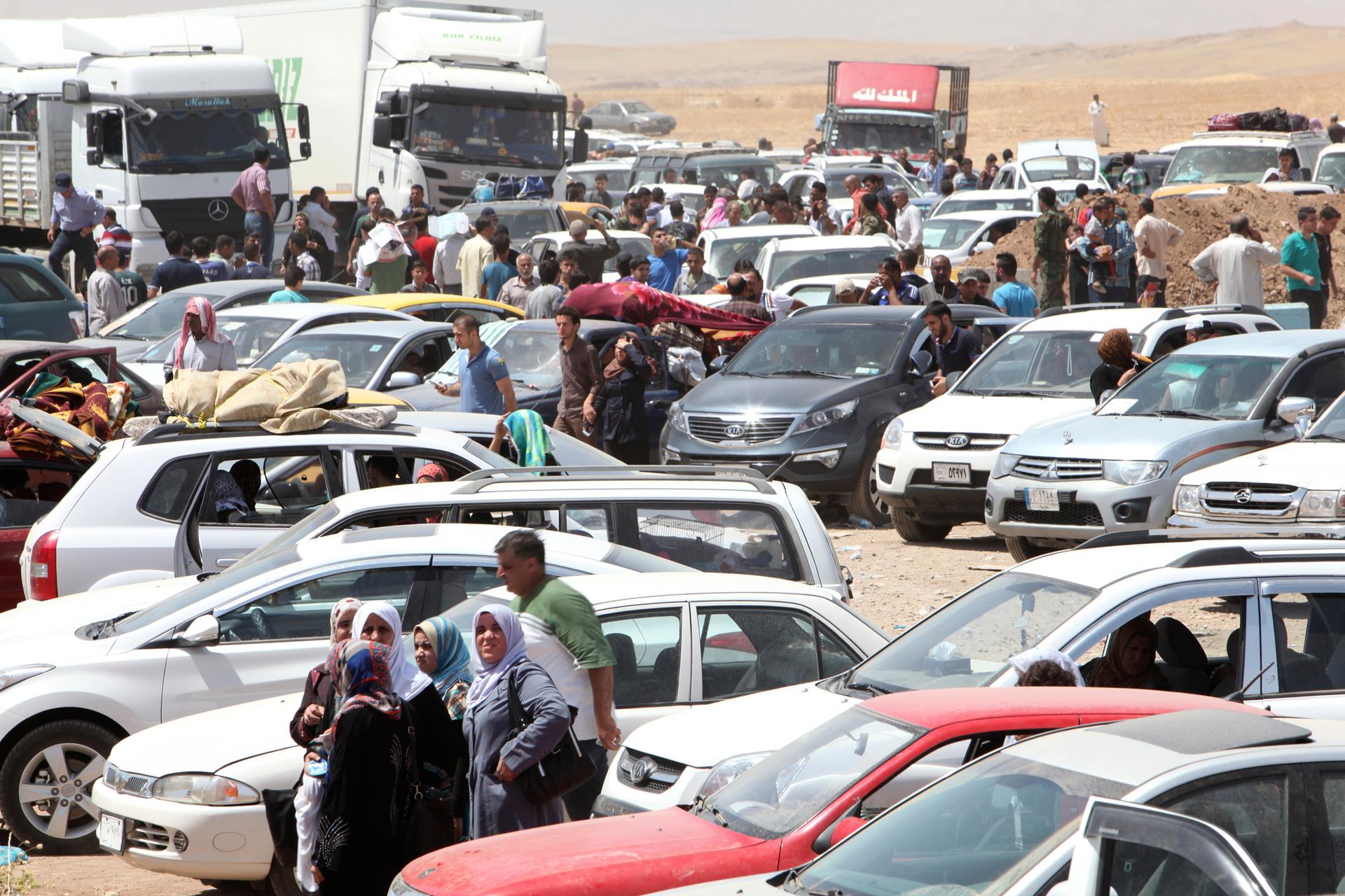 Families fleeing violence in northern wait at a checkpoint on the edge of Iraq's autonomous Kurdish region.  Half-a-million people are believed to have fled the city of Mosul in 24 hours. 