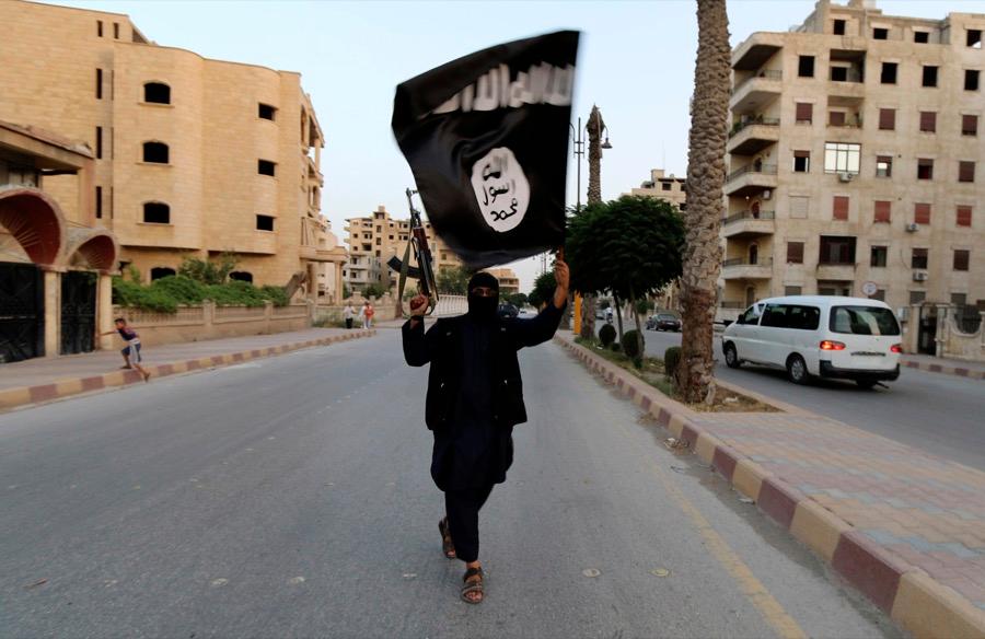 A member of ISIS waves the group's flag in Raqqa, Syria in June 2014.