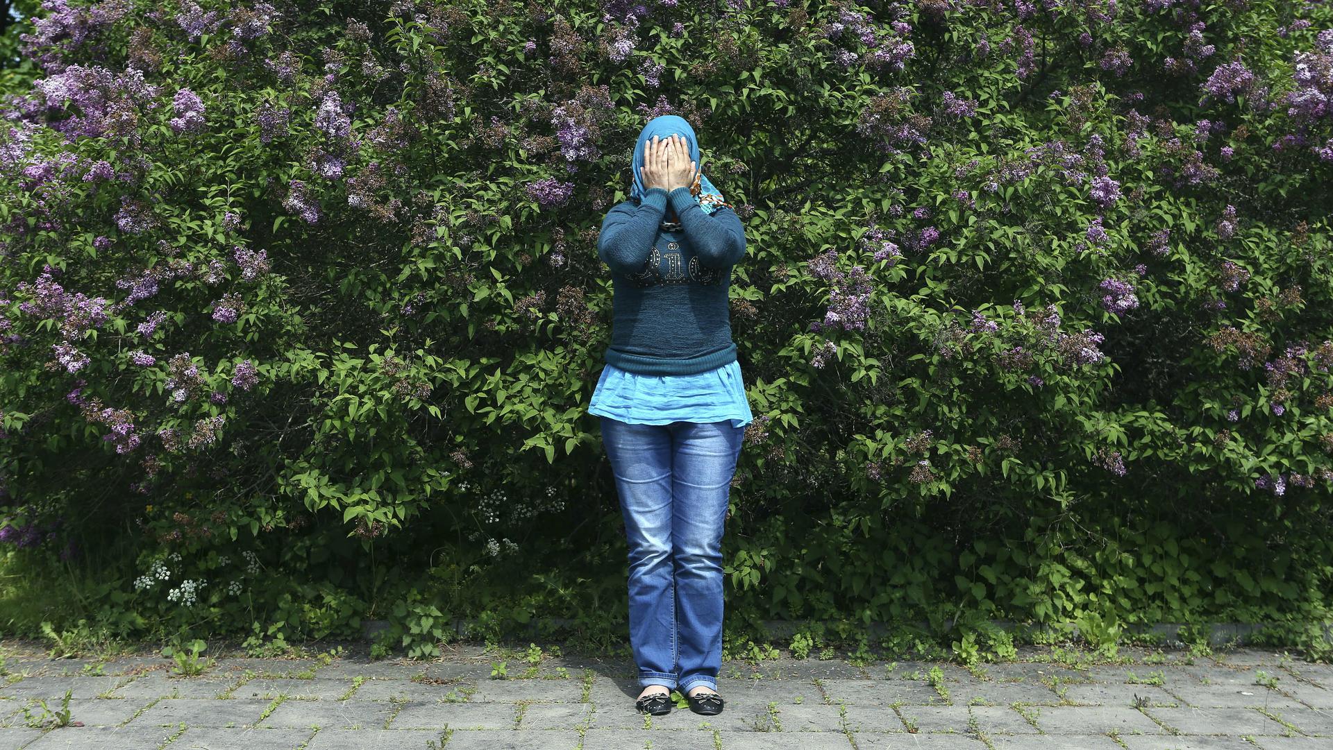 A Syrian refugee covers her face to hide her identity as she poses for a photograph at an asylum camp outside Stockholm, June 8, 2014.