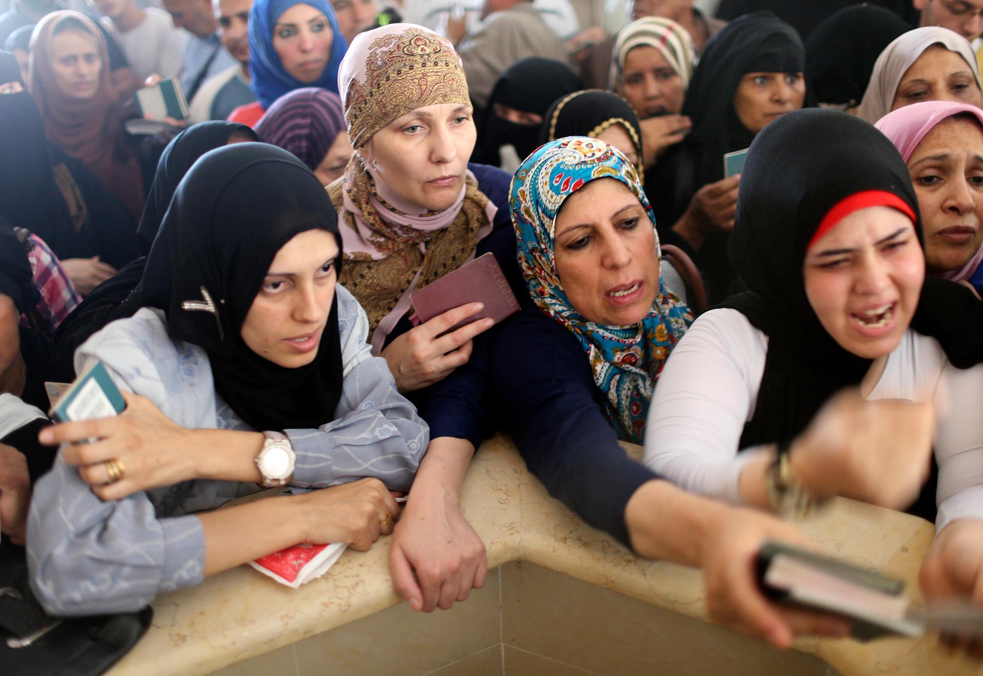 Women hoping to cross into Egypt present their passports as they wait at the Rafah crossing between Egypt and the southern Gaza Strip on July 12, 2014. Egypt's state news agency said Egyptian authorities had decided to open the Rafah border crossing to Ga