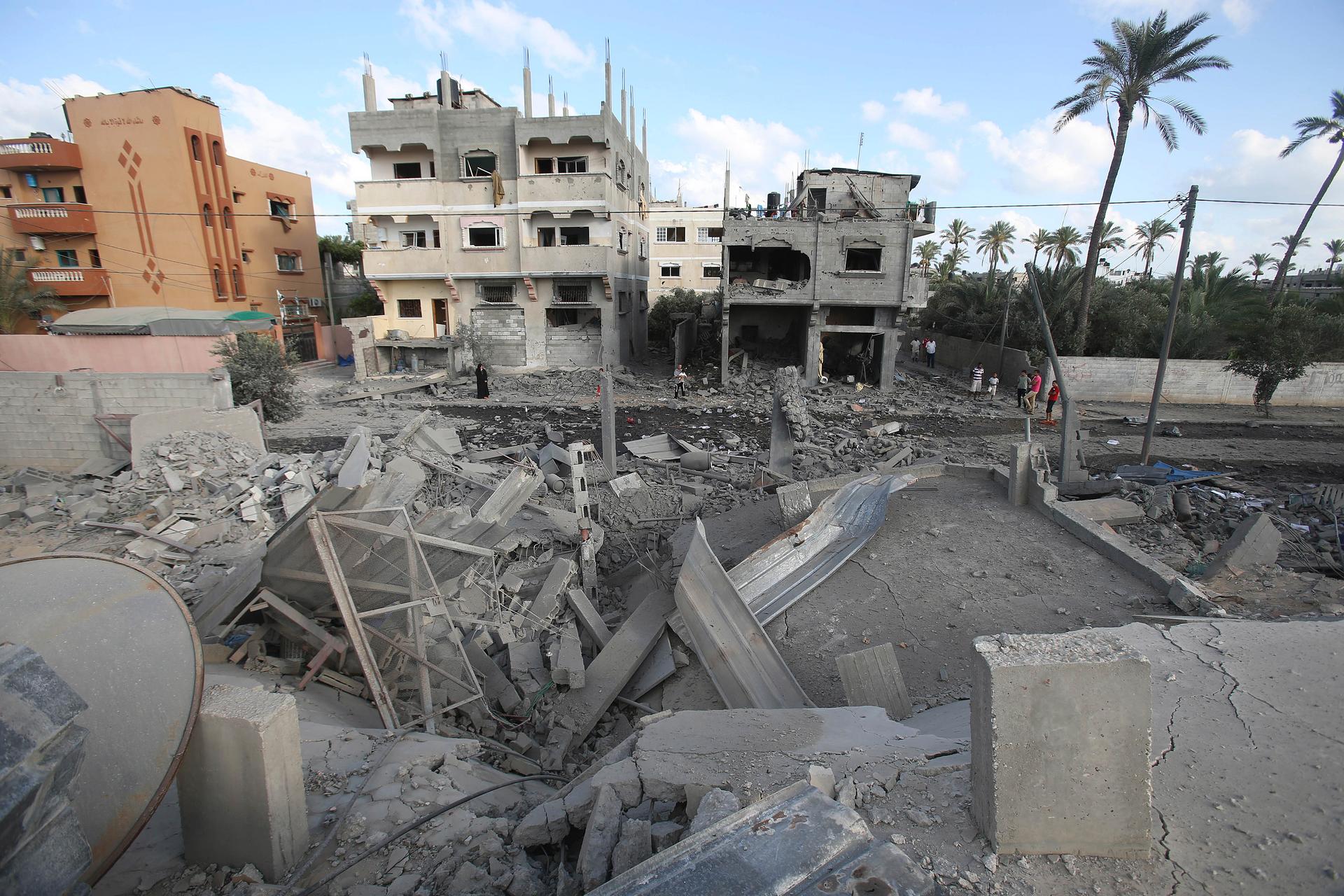 Palestinians look at the rubble of a house which police said was destroyed in an Israeli air strike in Deir El-Balah in the central Gaza Strip July 14, 2014.