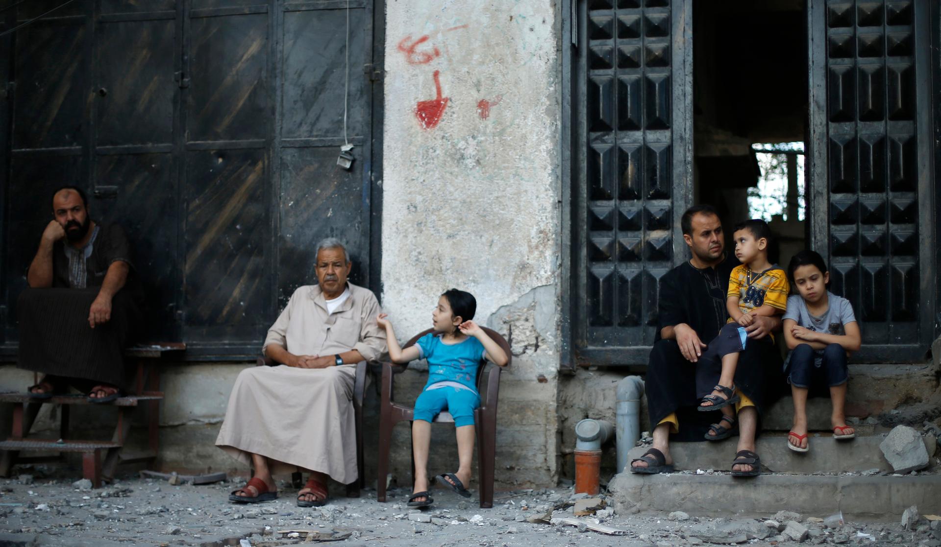 Palestinians sit outside their house that is located opposite to the house of top Hamas political leader Mahmoud Zahar which police said was targeted in an Israeli air strike in Gaza City