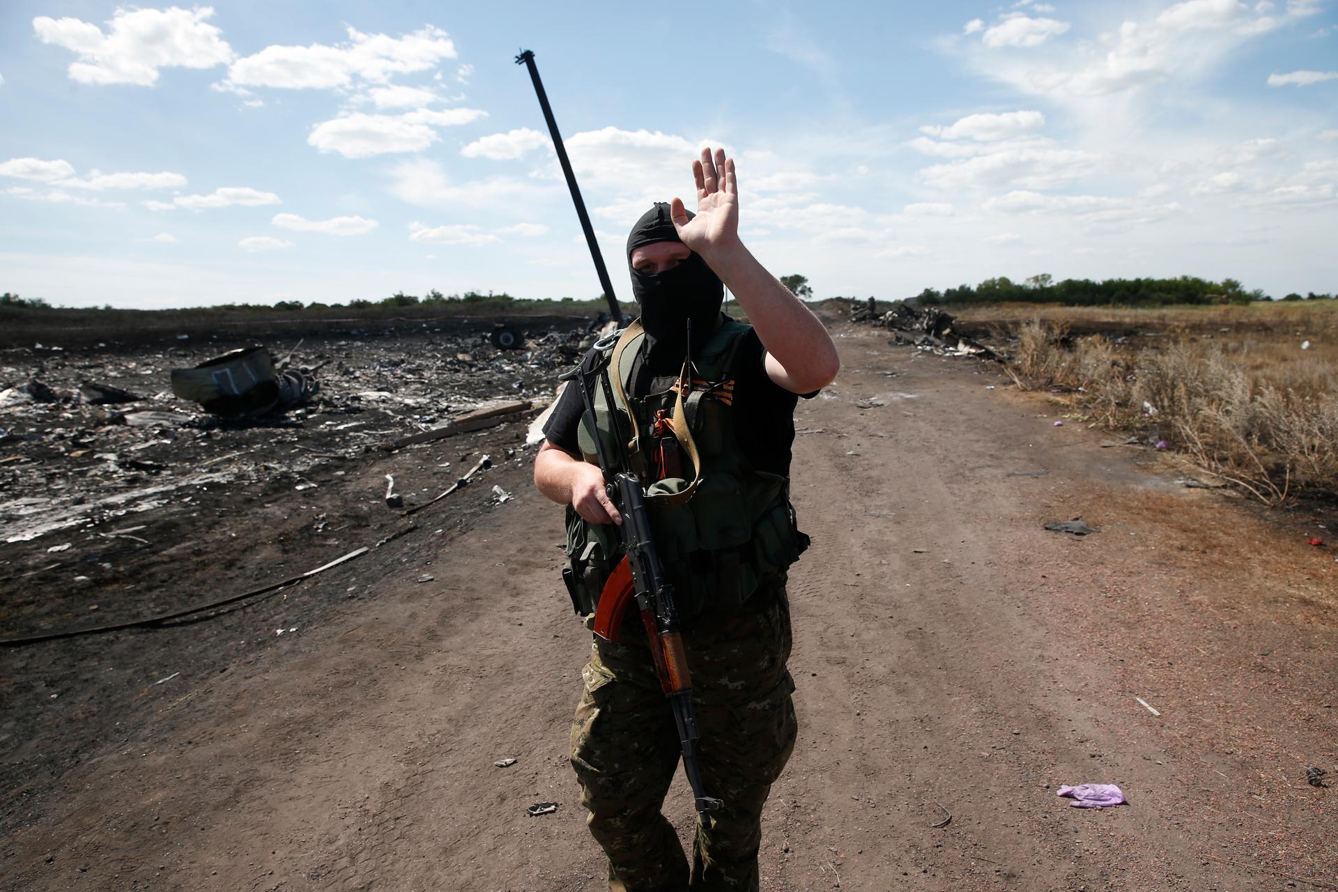 An armed pro-Russian separatist gestures to reporters at the crash site of Malaysia Airlines Flight MH17, near the village of Hrabove (Grabovo), Donetsk region July 21, 2014.
