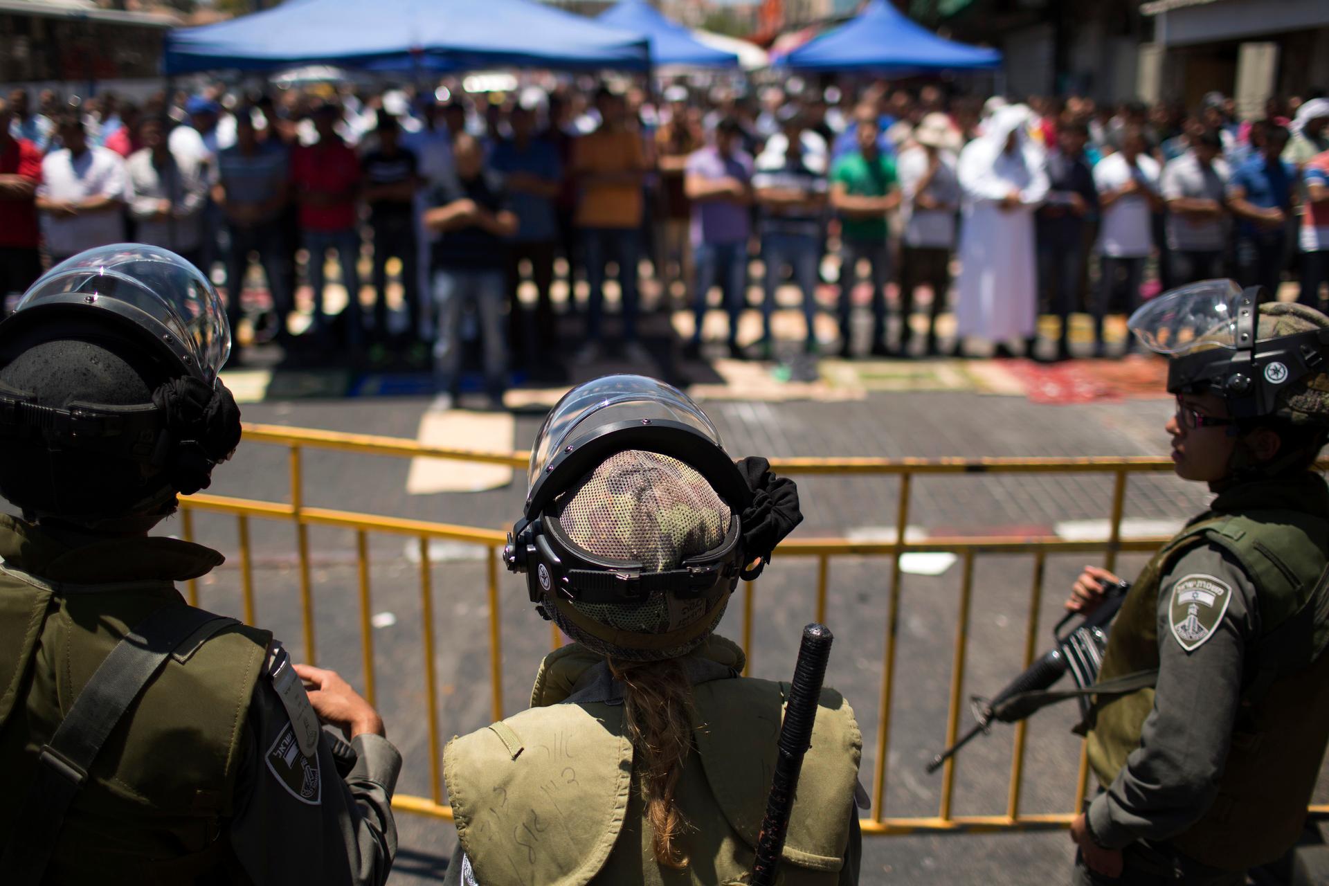 Israeli police stand guard behind as Palestinians pray on the last Friday of the holy month of Ramadan outside of the Old City in Jerusalem, on July 25, 2014.