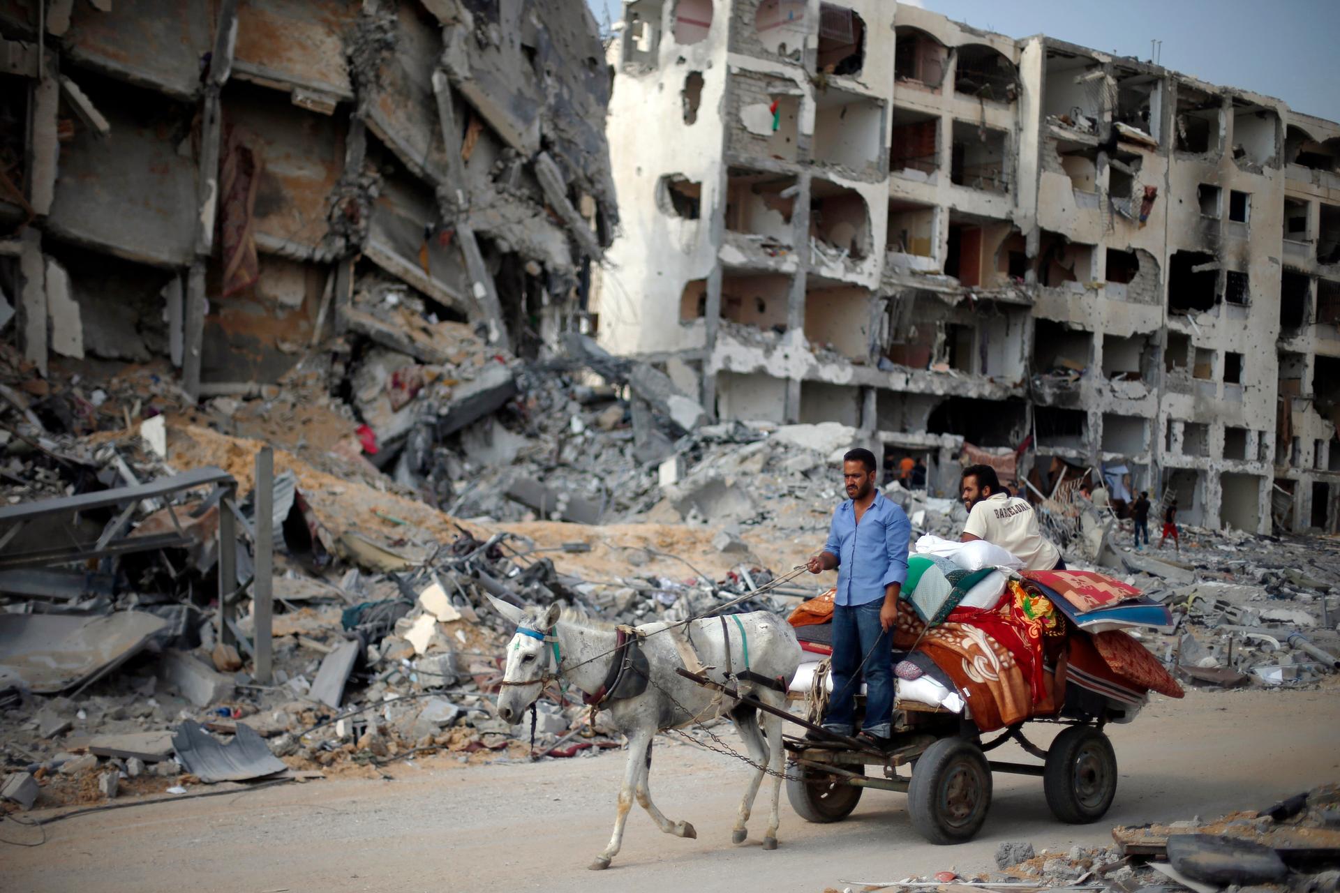 Palestinians ride a donkey cart past destroyed and badly damaged residential buildings as they return to Beit Lahiya town, which witnesses said was heavily hit by Israeli shelling and air strikes during the Israeli offensive.