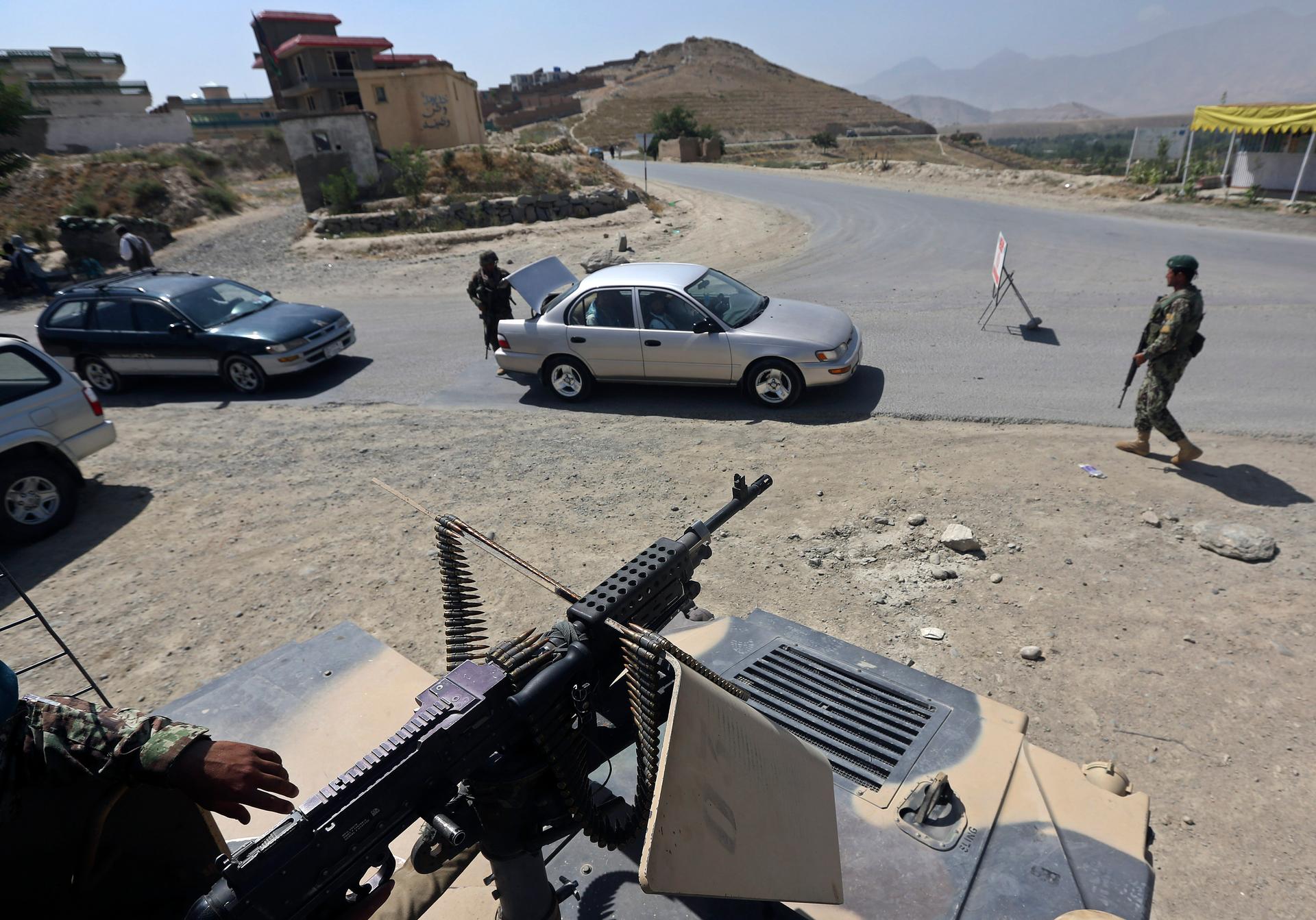 Afghan National Army soldiers inspect a car at a checkpoint near the British-run military training academy, Camp Qargha, in Kabul on August 6, 2014.