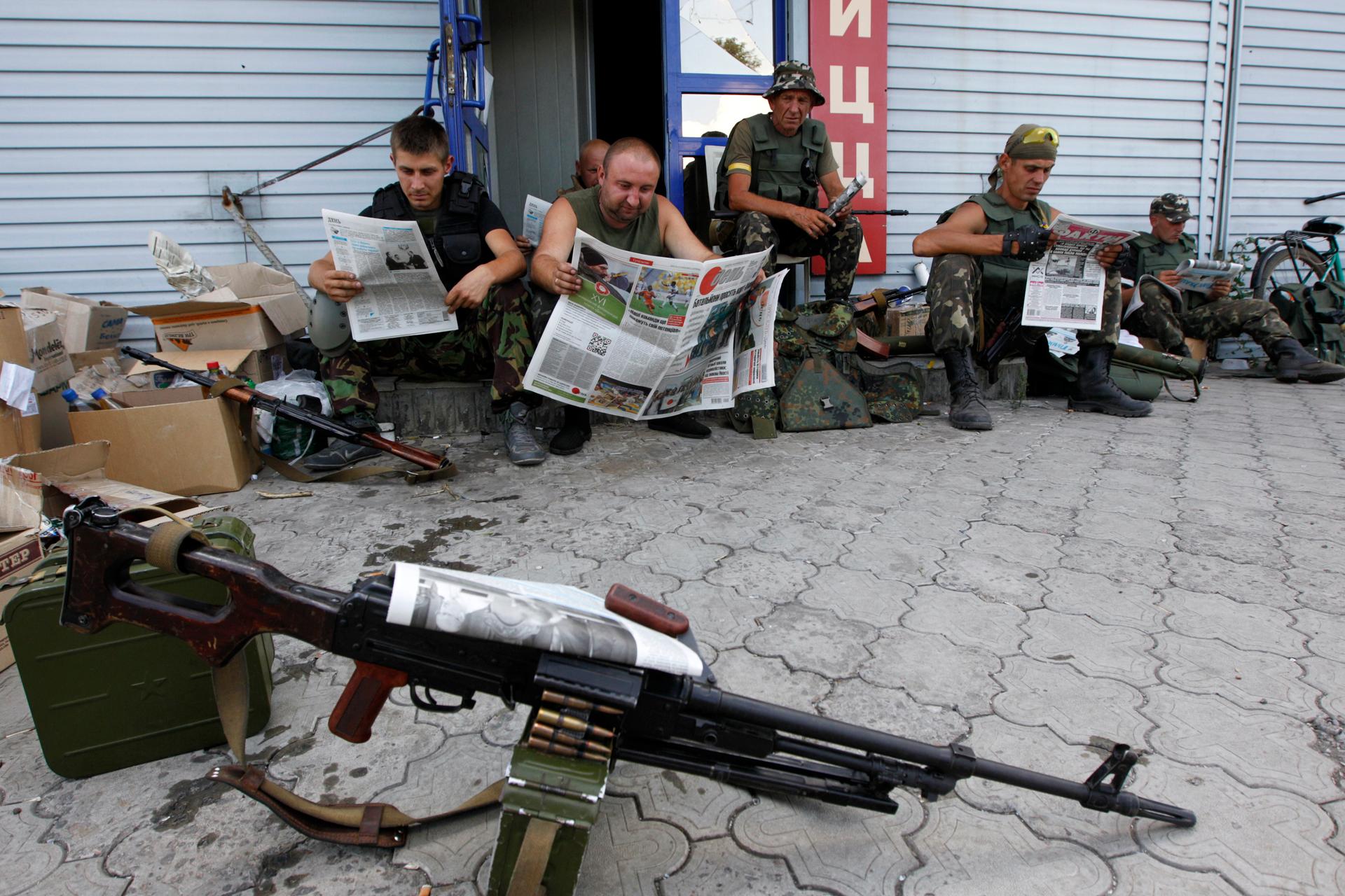 Ukrainian servicemen read newspapers as they rest at a checkpoint near the eastern Ukrainian town of Debaltseve in the Donetsk Region on August 6, 2014.