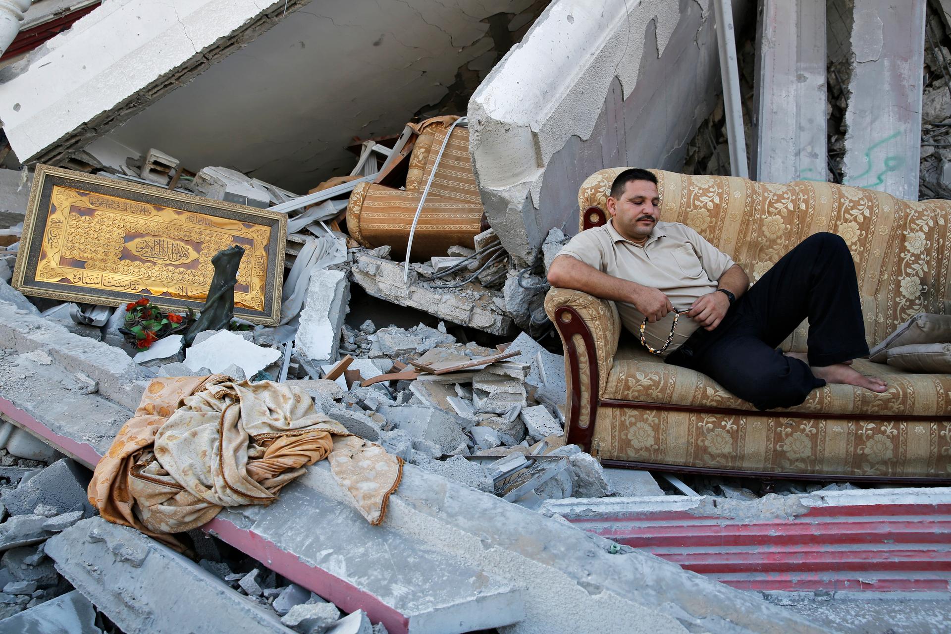 A man sits amid the ruins of destroyed homes in the Gaza Strip. Reconstruction cannot really start till Israel opens the frontier for cement and other building materials.