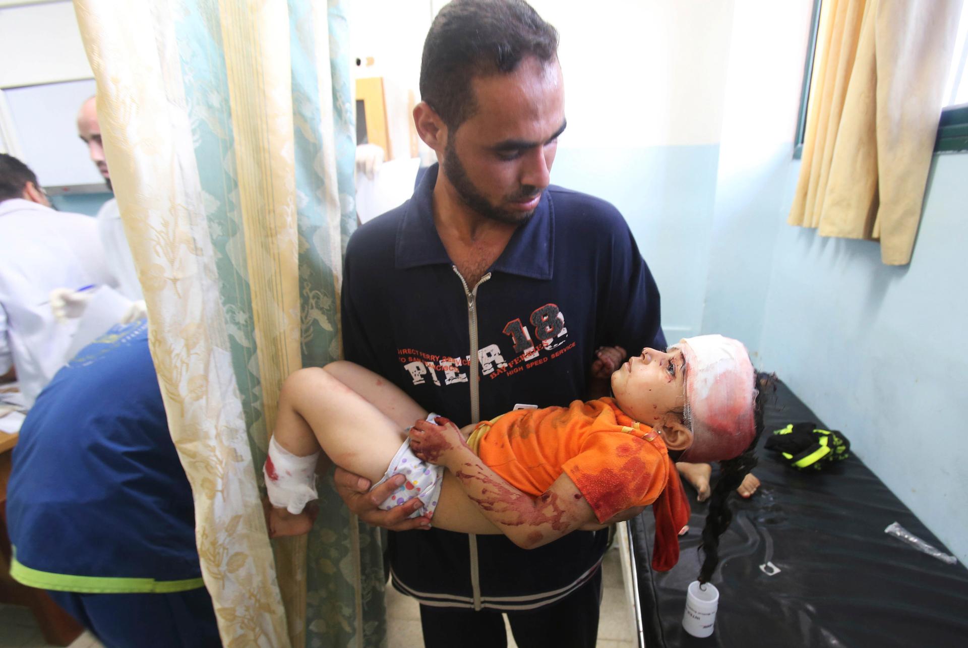 A man carries a Palestinian girl, whom medics said was wounded in an Israeli air strike, at a hospital in Khan Younis in the southern Gaza Strip, Friday.