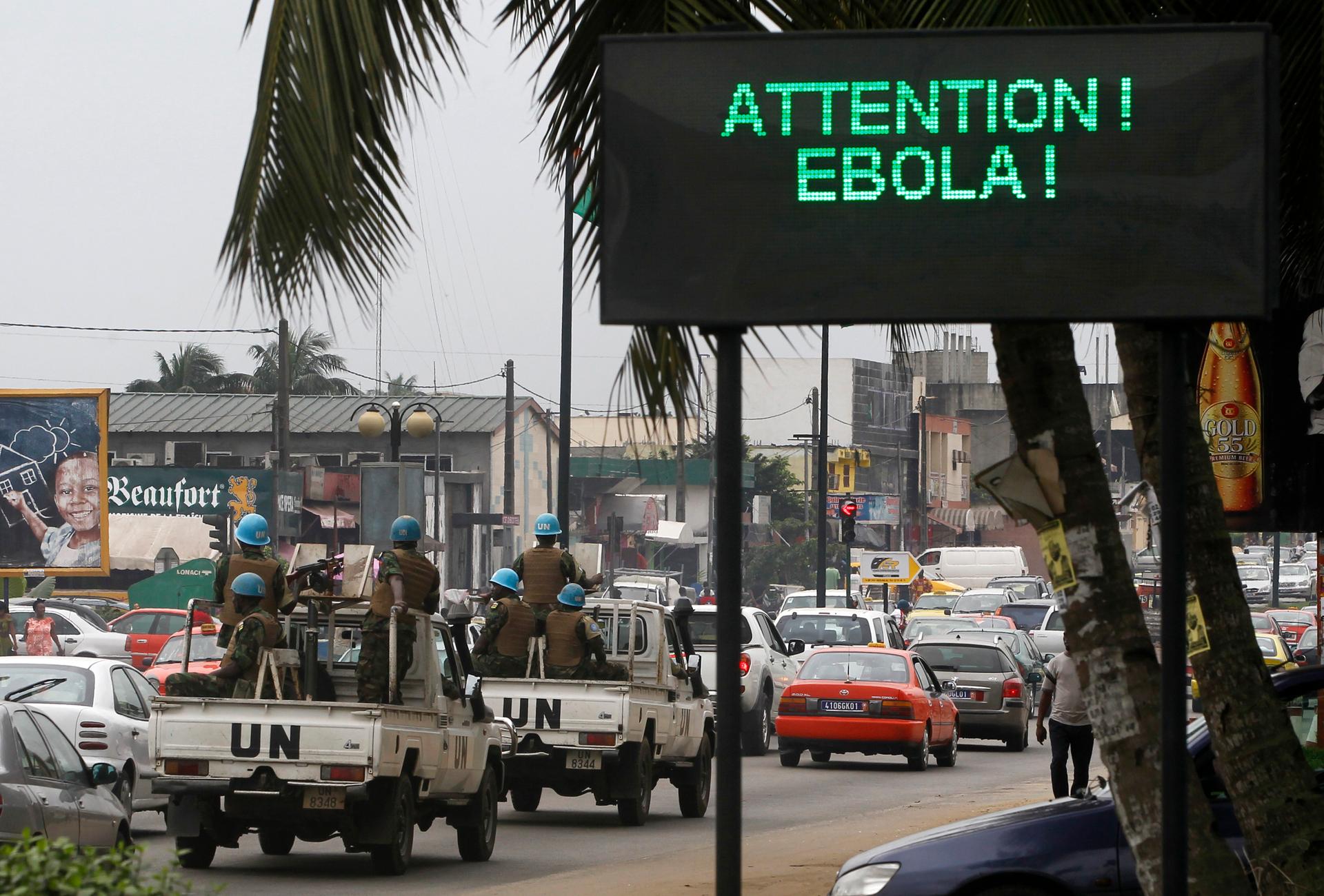 A UN convoy of soldiers passes a screen displaying a message about Ebola on a street in Abidjan, Ivory Coast, on August 14, 2014. 