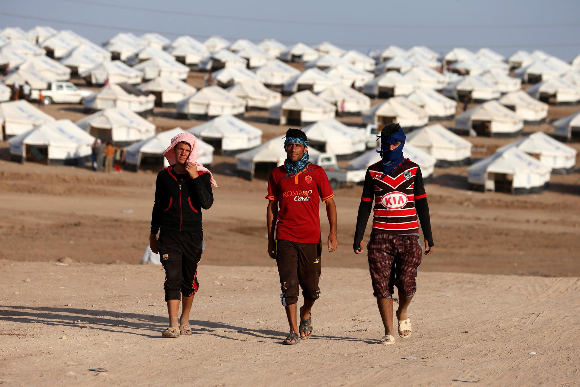 Displaced people from the minority Yazidi sect, who fled the violence in the Iraqi town of Sinjar, walk in the Bajed Kadal refugee camp southwest of Dohuk province on August 15, 2014. 