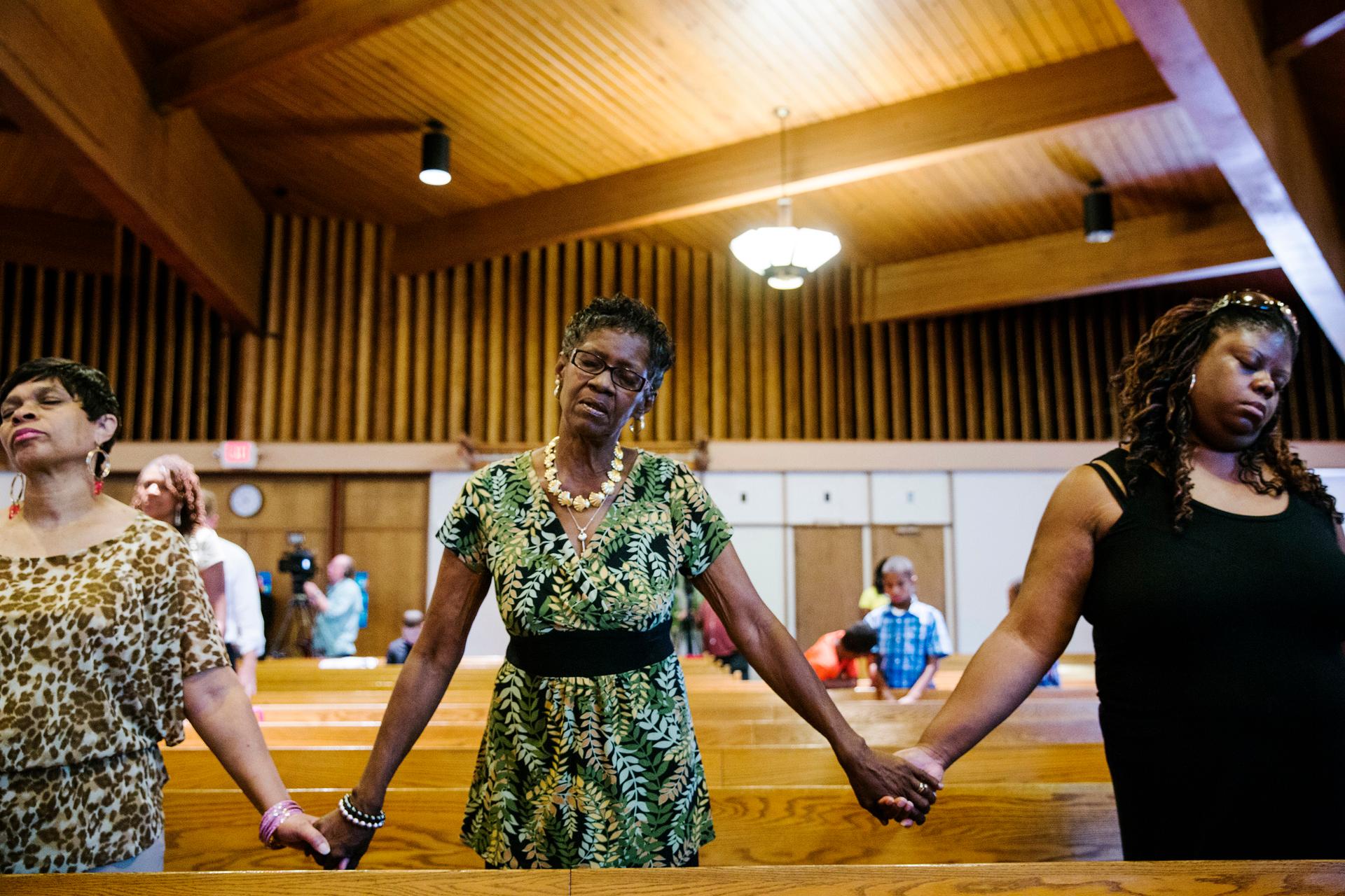 Parishioners hold hands during church services at the Greater St. Mark Family Church as the community discusses reactions to the shooting of teenager Michael Brown in Ferguson, Mo., on August 17, 2014.
