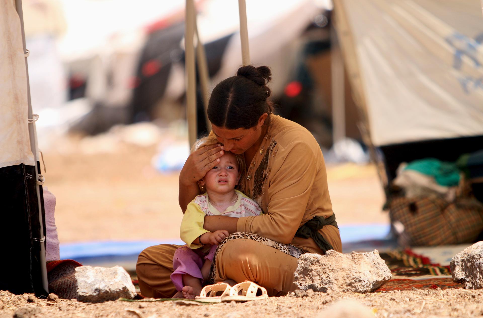 A refugee woman from the minority Yazidi sect, who fled the violence in the Iraqi town of Sinjar, sits with a child inside a tent at a refugee camp in north-eastern Syria. The Yazidis have been brutally persecuted by militants from the Islamic State, some