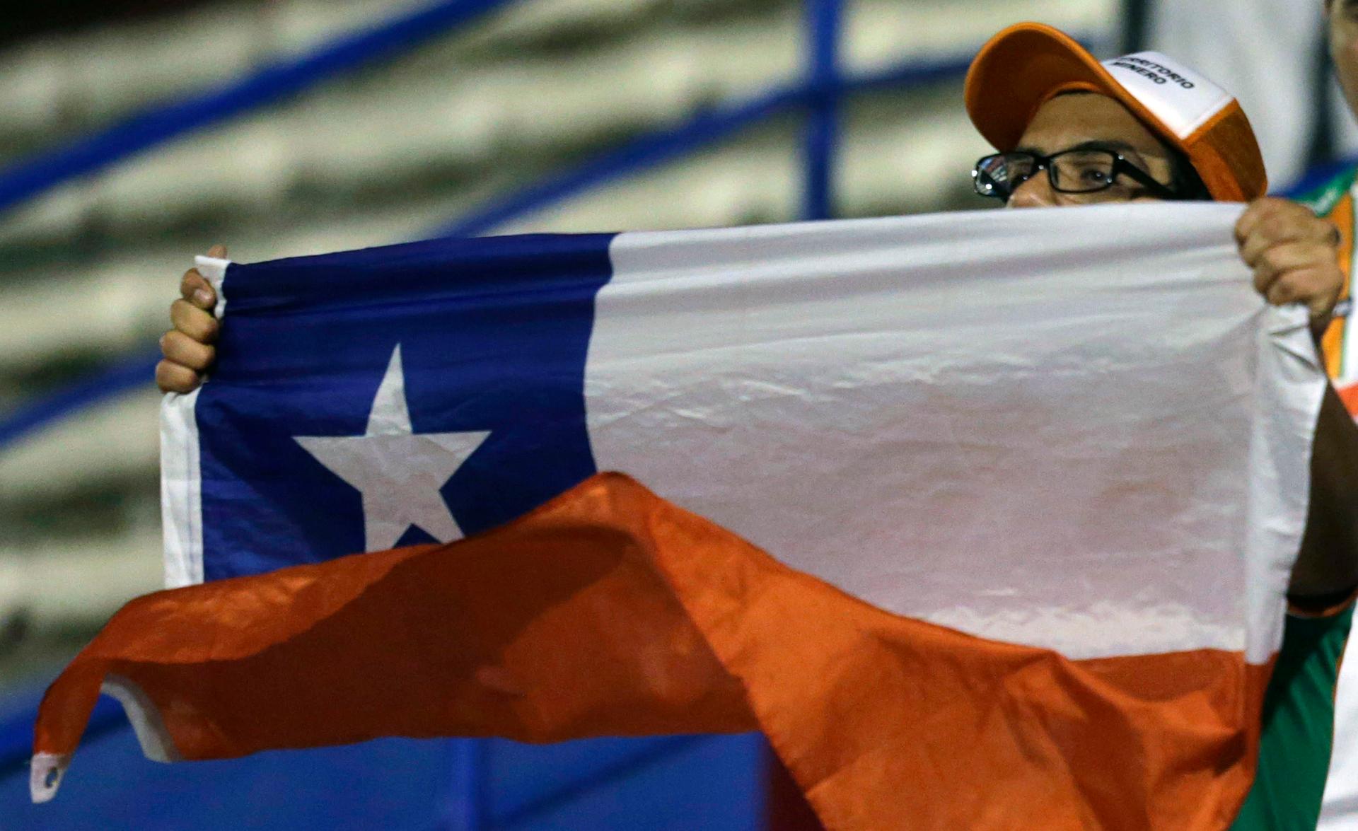 A fan of Chile's Cobresal holds a Chilean national flag before his team plays against Paraguay's General Diaz in their Copa Sudamericana soccer match in Luque near Asuncion, August 20, 2014.