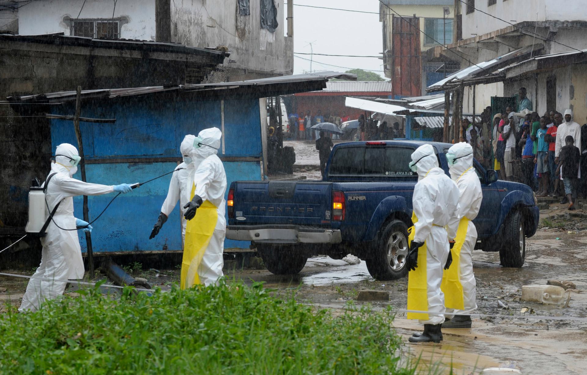 Health workers wearing protective clothing disinfect themselves after an abandoned dead body presenting with Ebola symptoms was found at Duwala market in Monrovia, Liberia, on August 17, 2014.