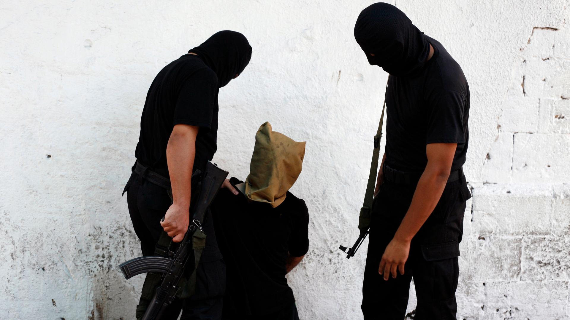 Hamas militants grab a Palestinian suspected of collaborating with Israel before being executed in Gaza City on August 22, 2014. Hamas militants killed seven Palestinians suspected of collaborating with Israel in a public execution in a central Gaza squar