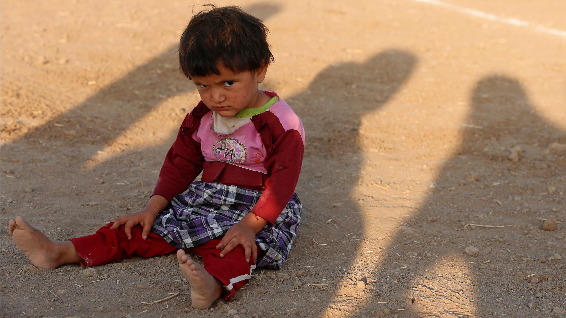 A child from the minority Yazidi sect, who fled violence in the Iraqi town of Sinjar, sits on the ground at Bajed Kadal refugee camp, southwest of Dohuk province August 23, 2014.