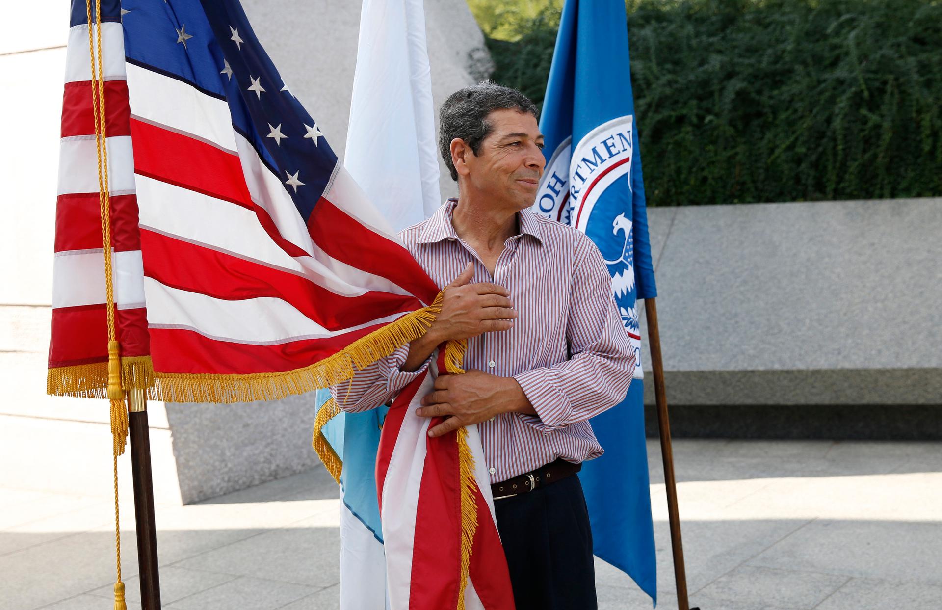 Brahim Djahra, from Algeria, clings to the Americans flag during a special naturalization ceremony held at the Martin Luther King Jr. Memorial in Washington on August 28, 2014.